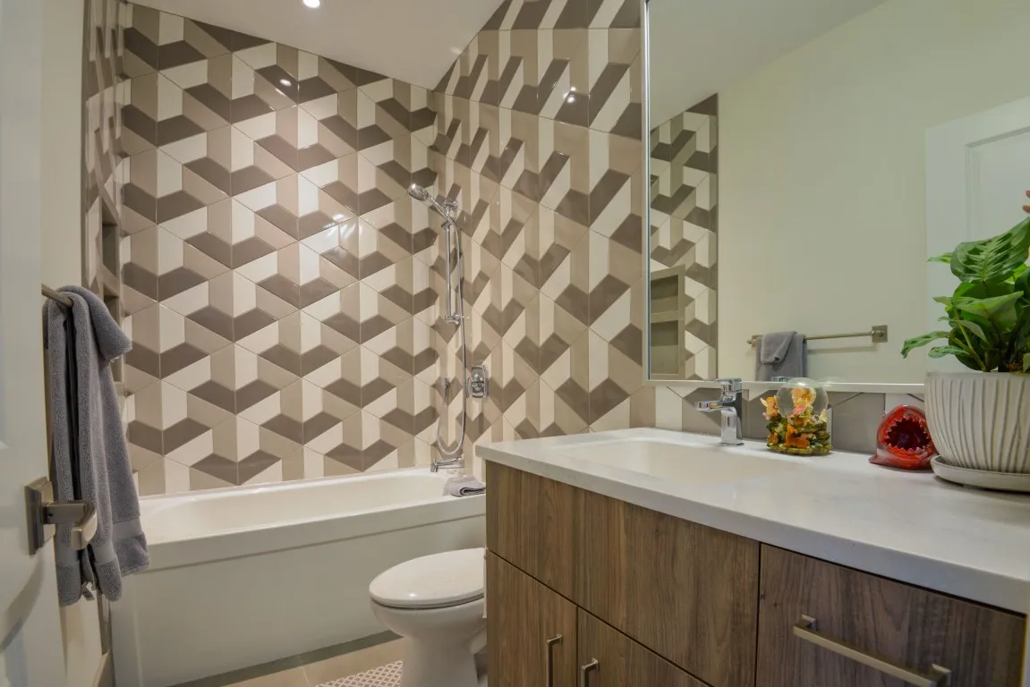 Image of Luxurious primary ensuites with modern geometric tile work and wooden vanities by KHD Homes design-build.