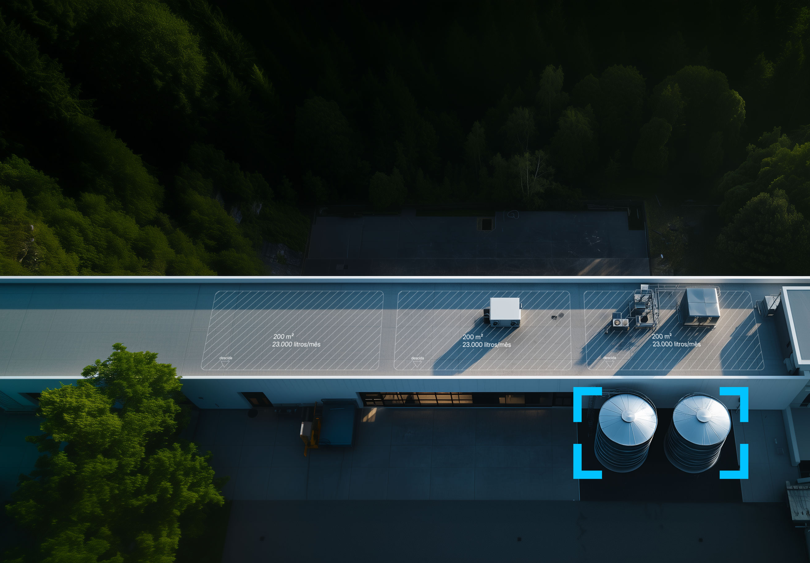 vista aérea do telhado de um edifício industrial com dois grandes reservatórios de água da chuva adossados ao exterior e, ao fundo, um bosque