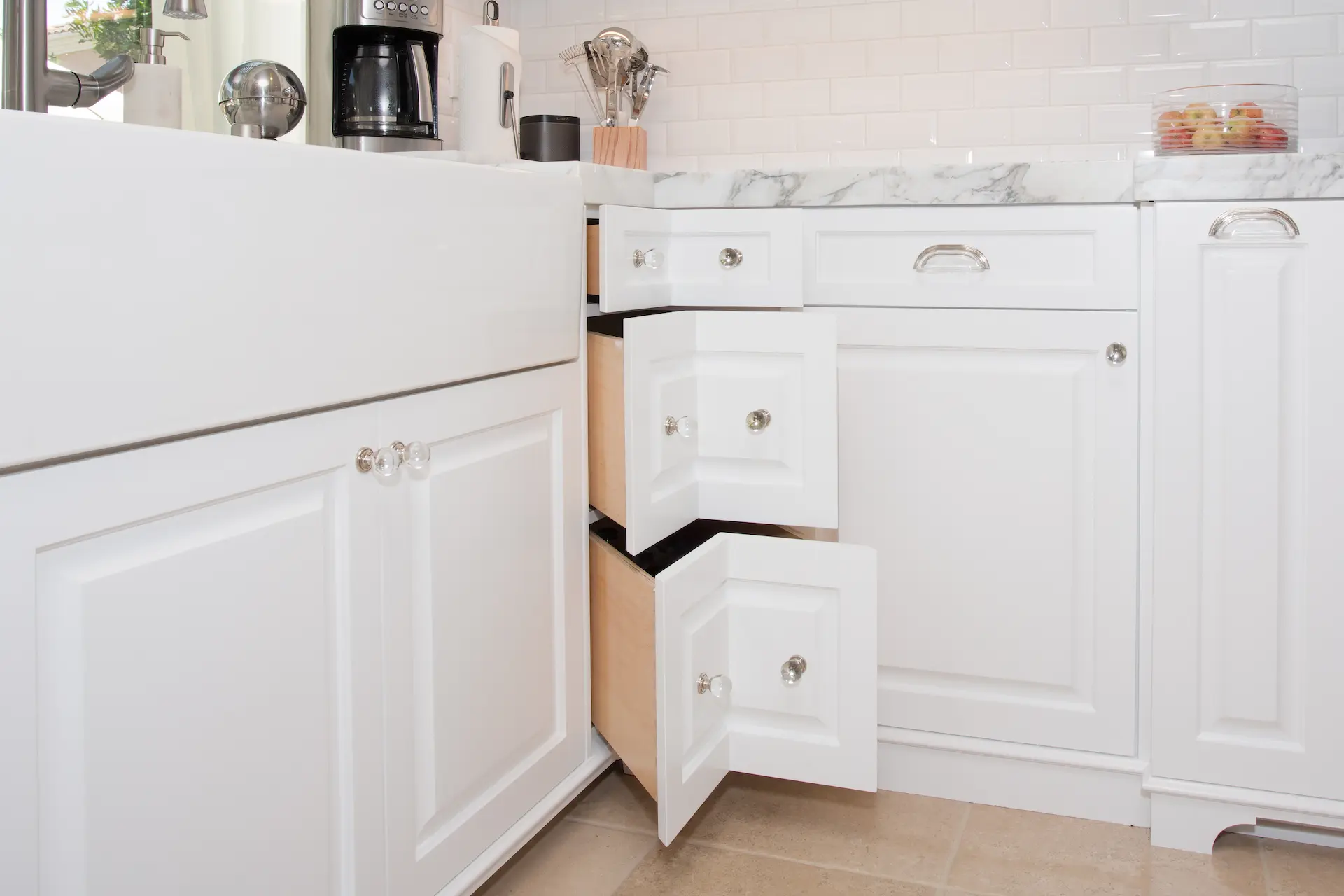 Corner drawers in white with black knobs against subway tile backsplash, Newport Beach Remodel.