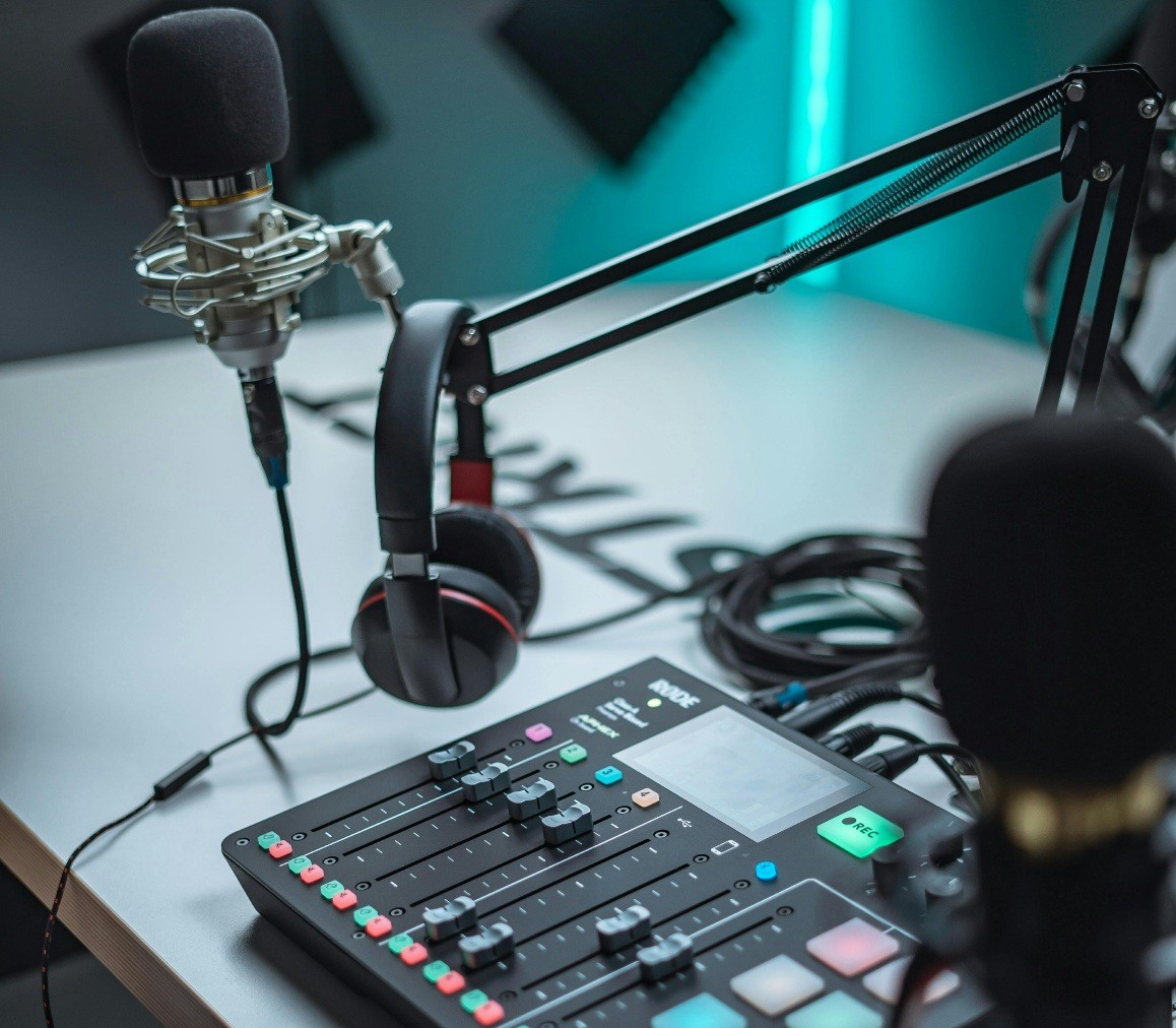 Podcasting setup with a microphone on an adjustable arm, a pair of headphones, and an audio mixing console on a desk, ready for recording