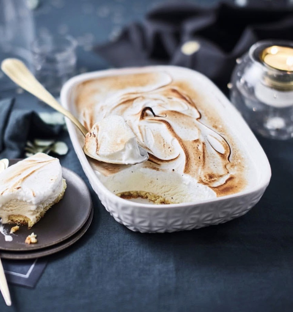 Plat rectangulaire en céramique blanche avec relief floral, garni d'une meringue dorée au chalumeau, servi avec cuillère dorée