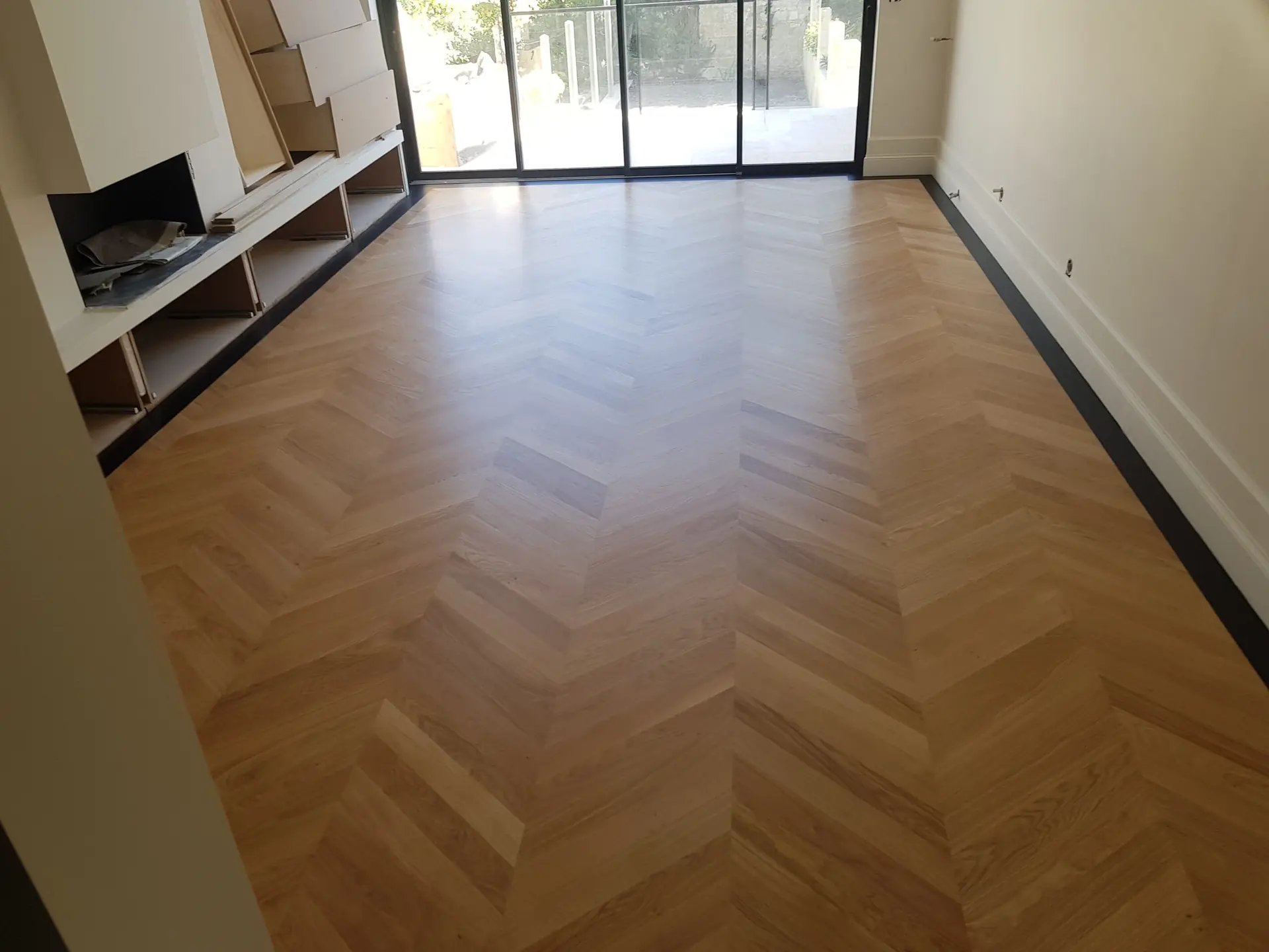 Parquet à motif en chevrons dans une pièce avec baie vitrée, photographié dans la galerie Aliénor