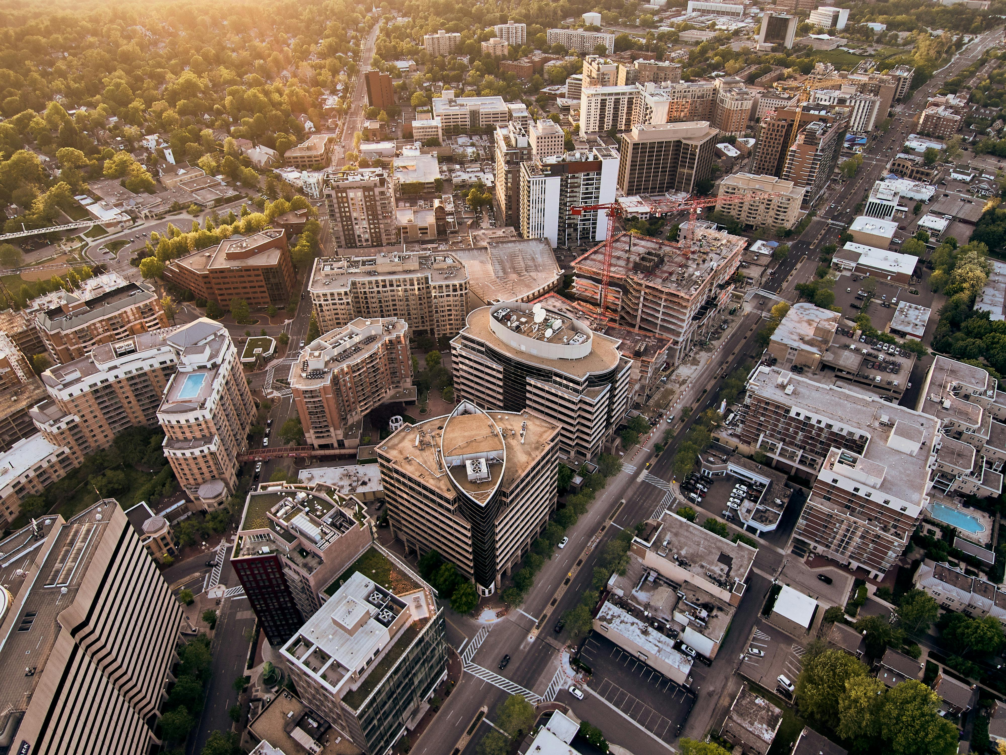 Aerial view of a modern cityscape with tall buildings and tree-lined streets.
