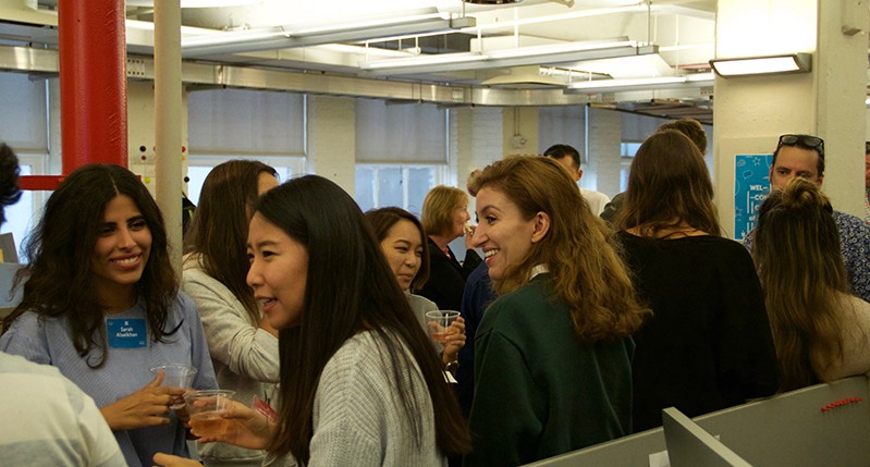 A photo of a group of people sitting in an office room and talking.