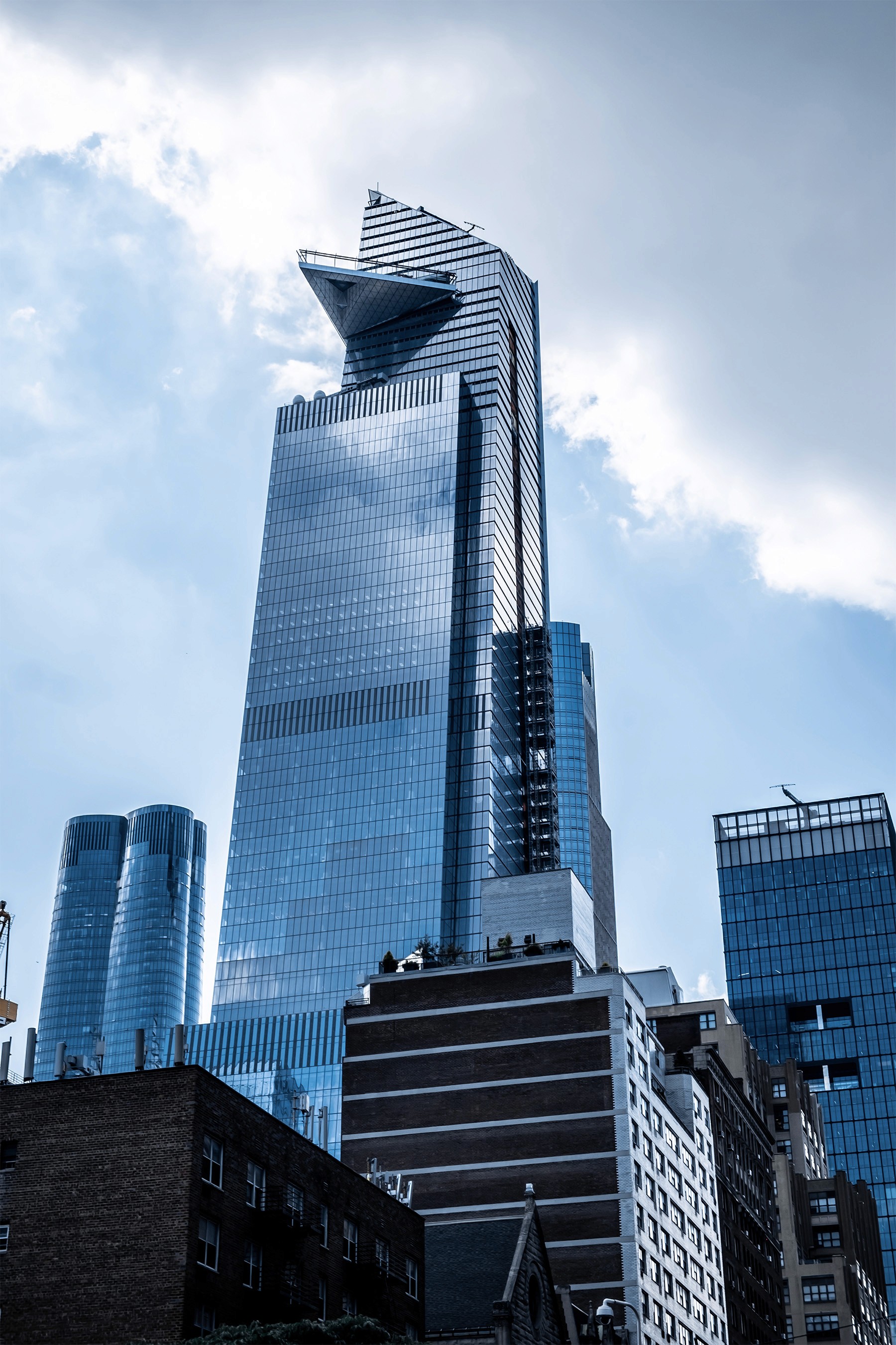 Modern glass skyscraper with angular architecture under a partly cloudy sky