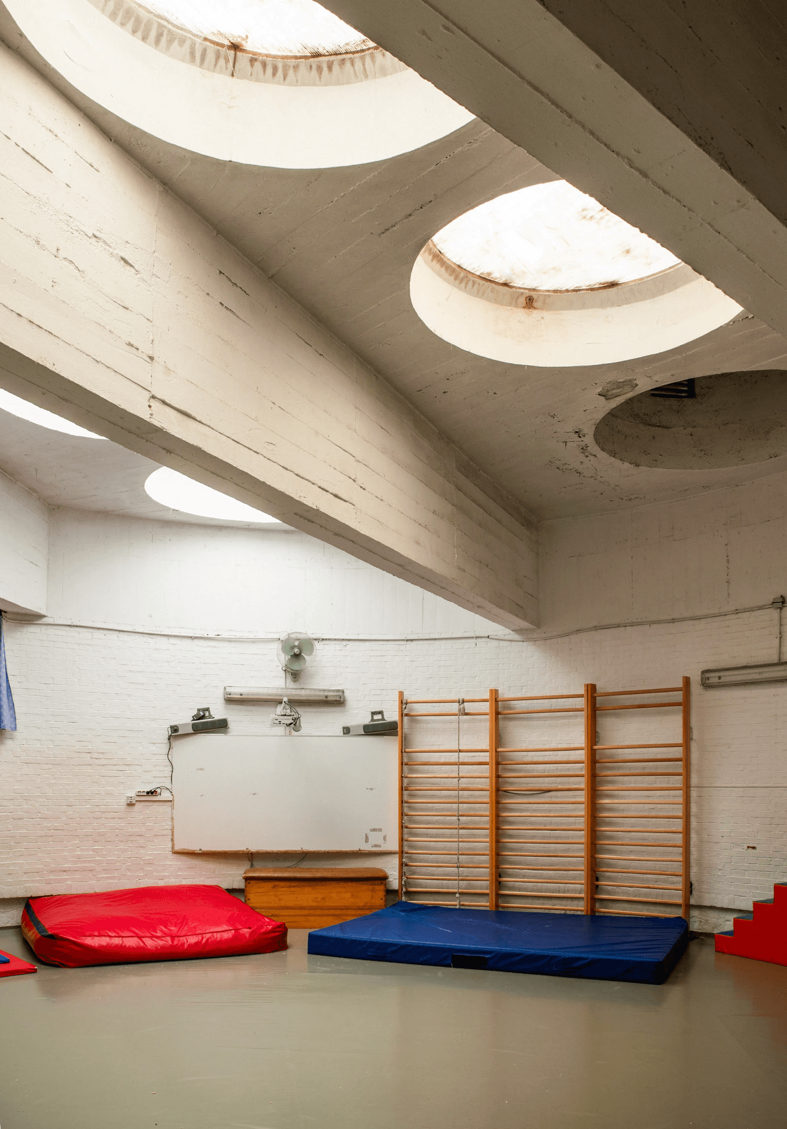 Gymnasium with circular skylights and sports equipment at Los Círculos de Oíza school