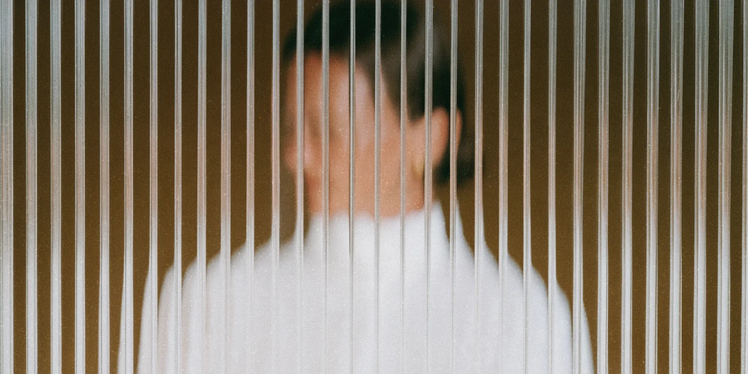 Person obscured behind textured privacy glass.