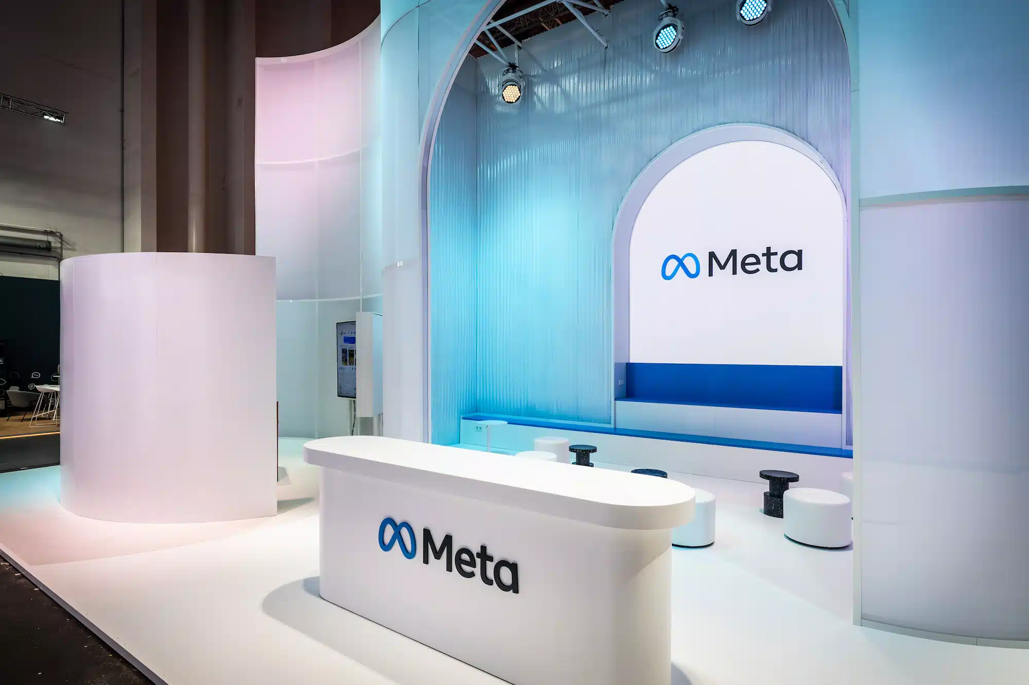 Meta – reception counter of the trade show booth with blue illuminated arch background and Meta logo