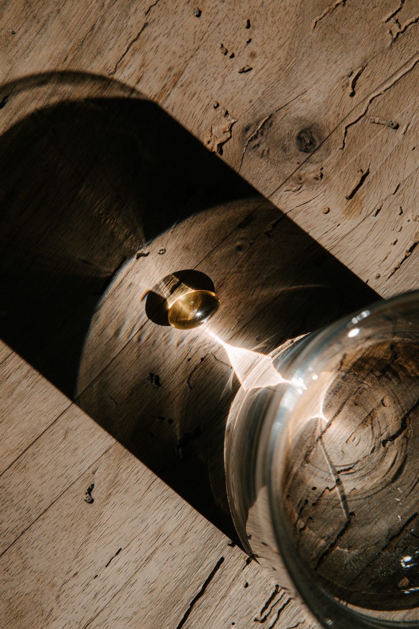 Sonnenlicht fällt durch Glas auf Holztisch mit Omega-3 Softgel-Kapseln