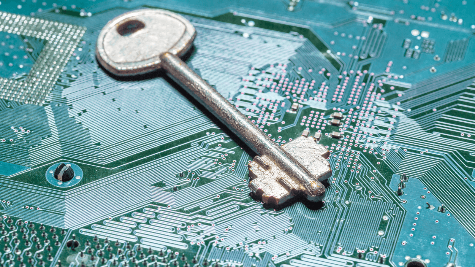 A silver key resting on a textured, turquoise surface with some scratches and reflections.