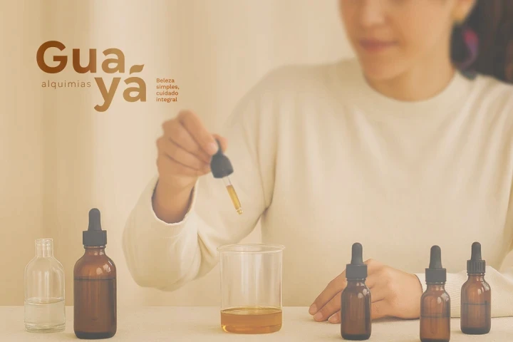 Uma mulher com roupas brancas utilizando conta gotas com alguns óleos essenciais sobre a mesa.