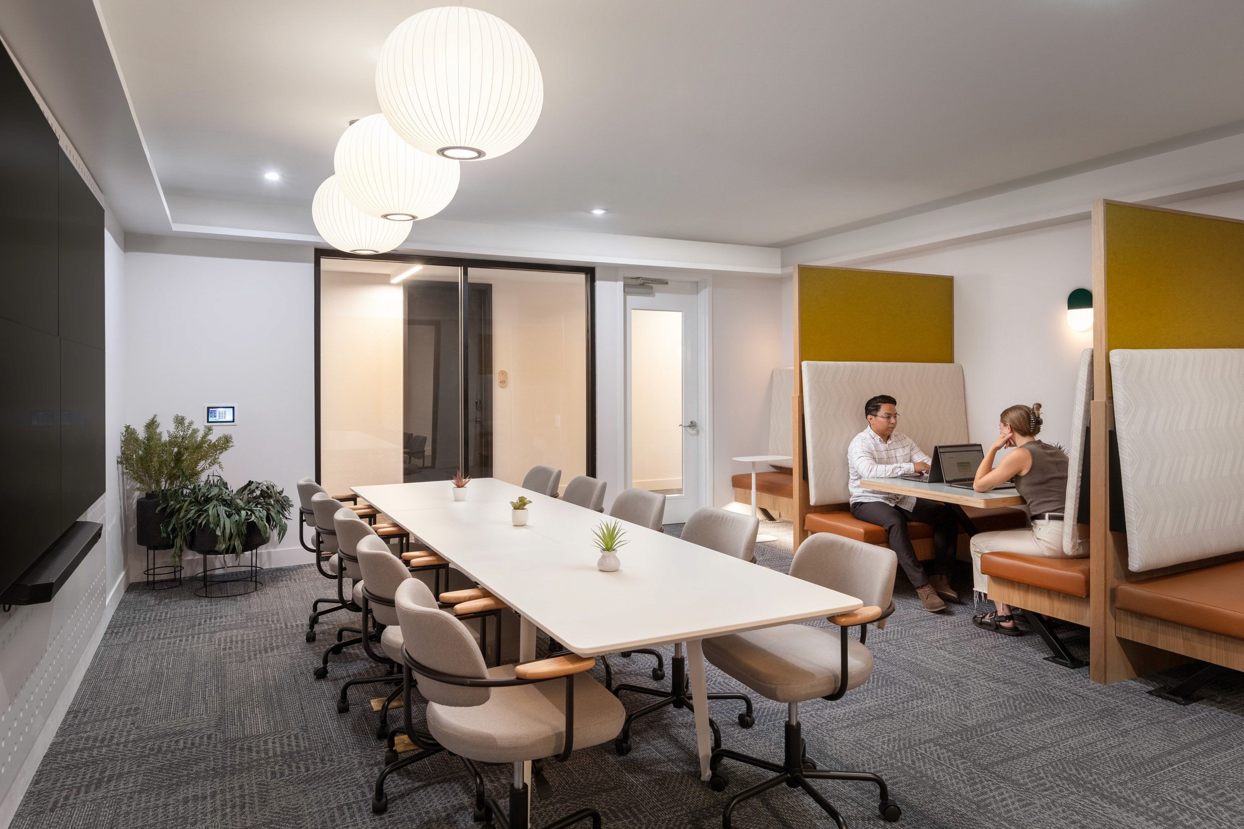 Conference room with long table and two people working at booths