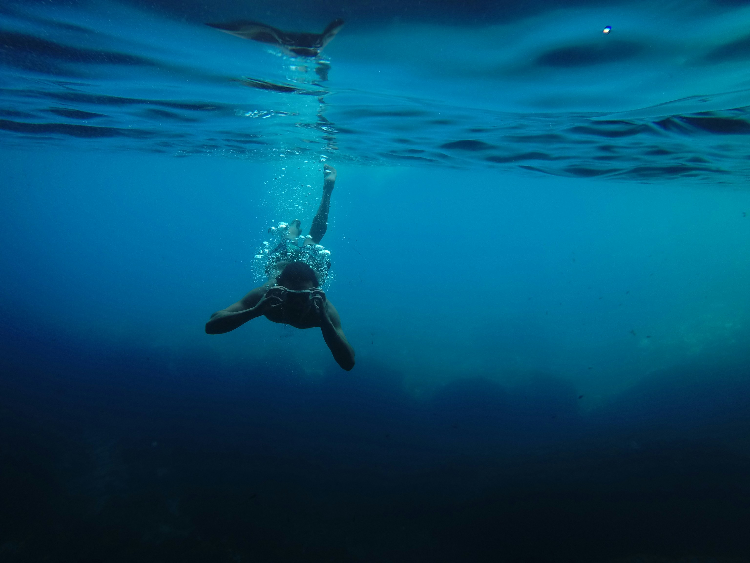 person wearing goggles while swimming under body of water