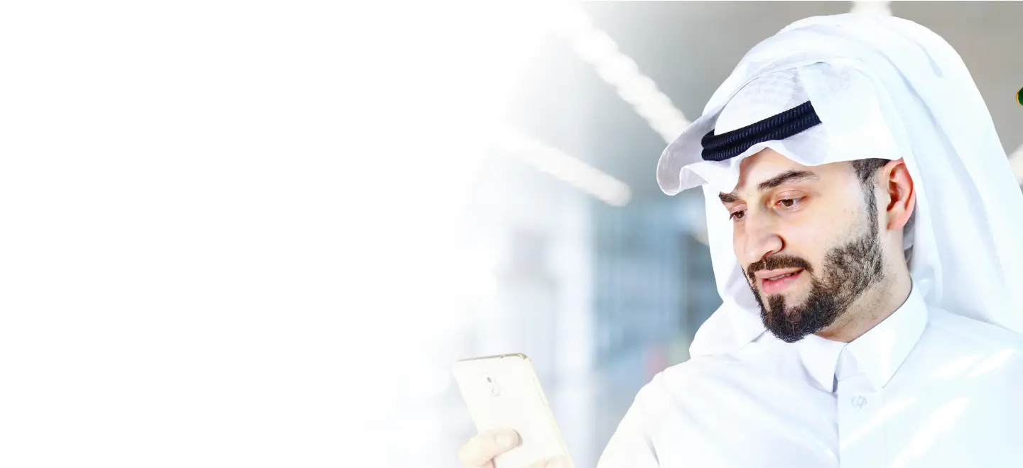 A Middle Eastern man in traditional attire looking at his smartphone, using a digital health app, representing the use of technology in managing chronic conditions like diabetes.