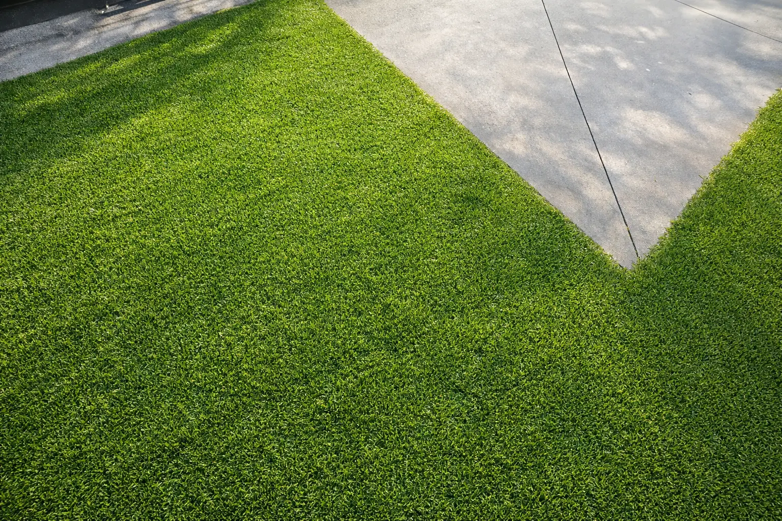 Artificial turf landscaping installed alongside modern concrete patio.
