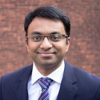 Black girl wearing glasses in a passport-style headshot on plain background.
