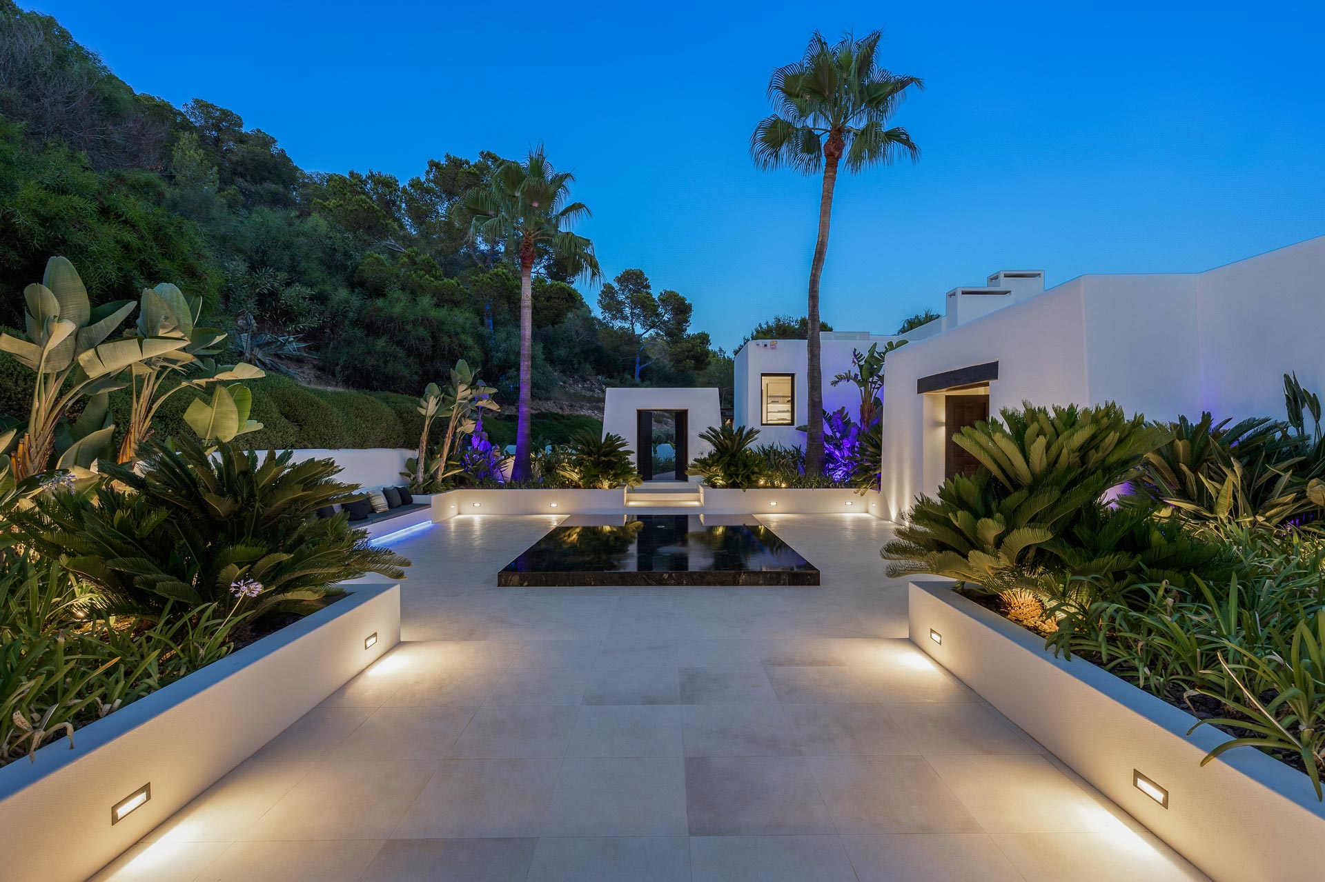 Estate entrance courtyard with water feature, landscape lighting and Mediterranean night garden design.