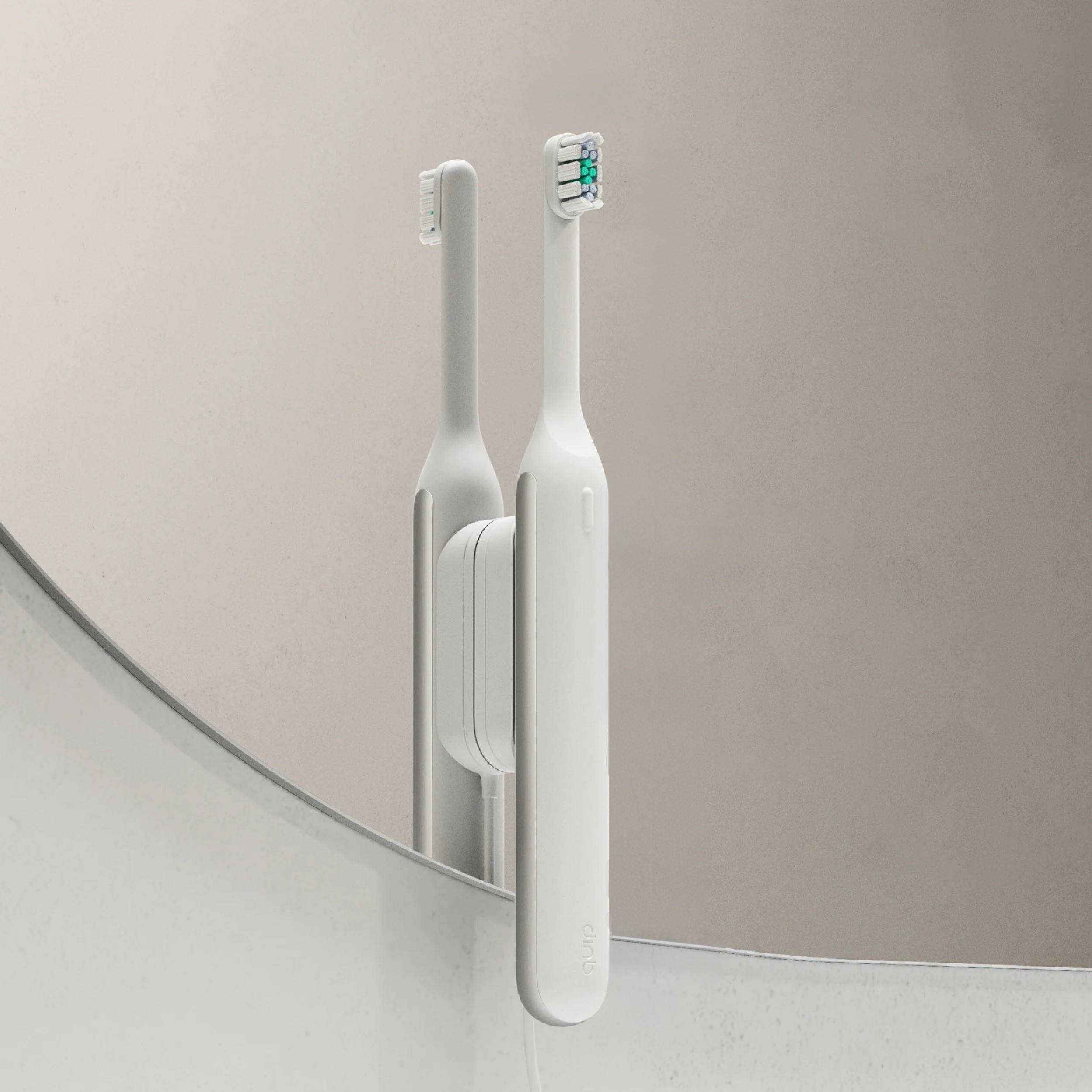 A white quip Ultra held to a mirror by its magnetic mount.