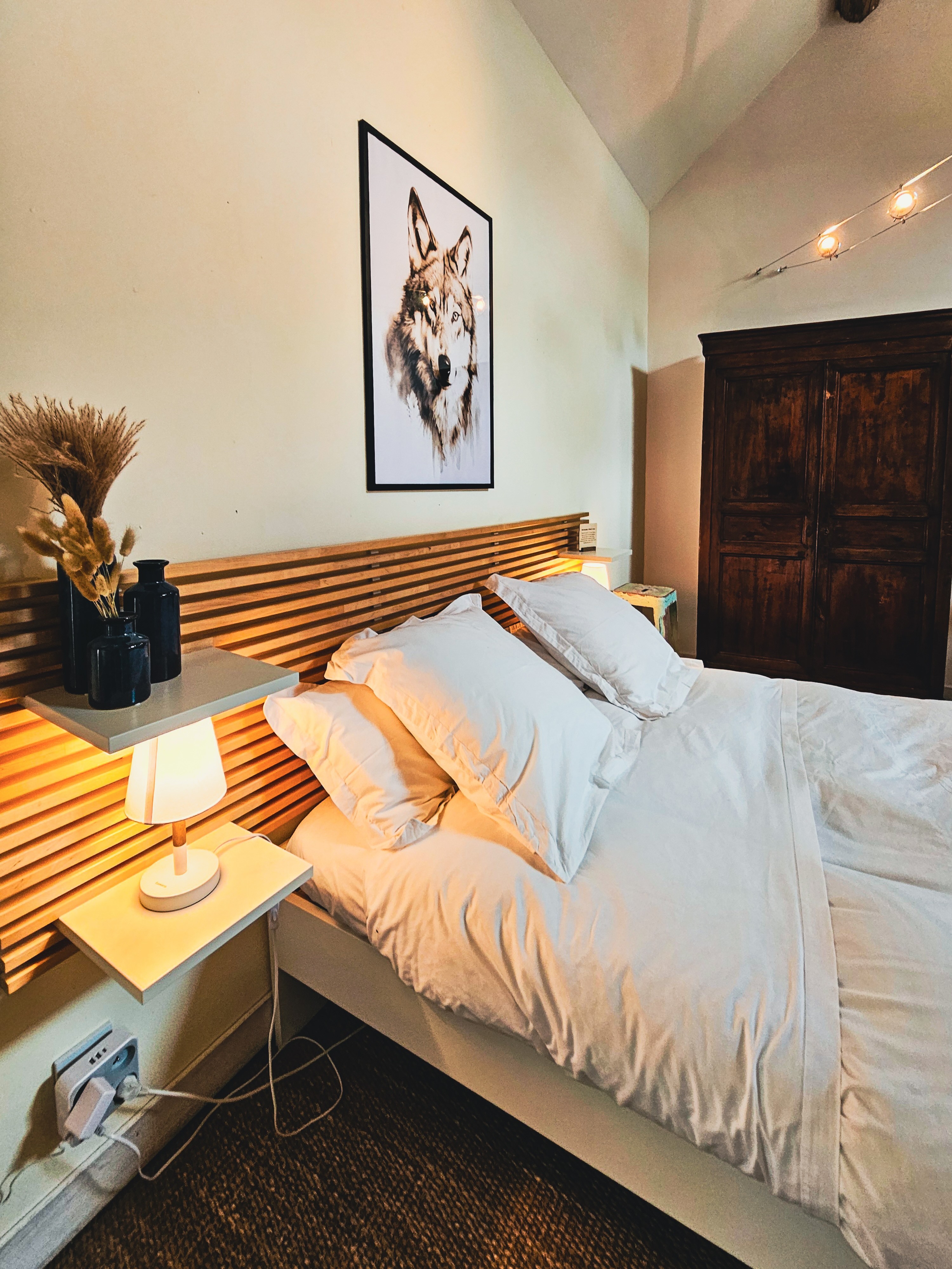 Une chambre avec un lit blanc et un tableau de loup