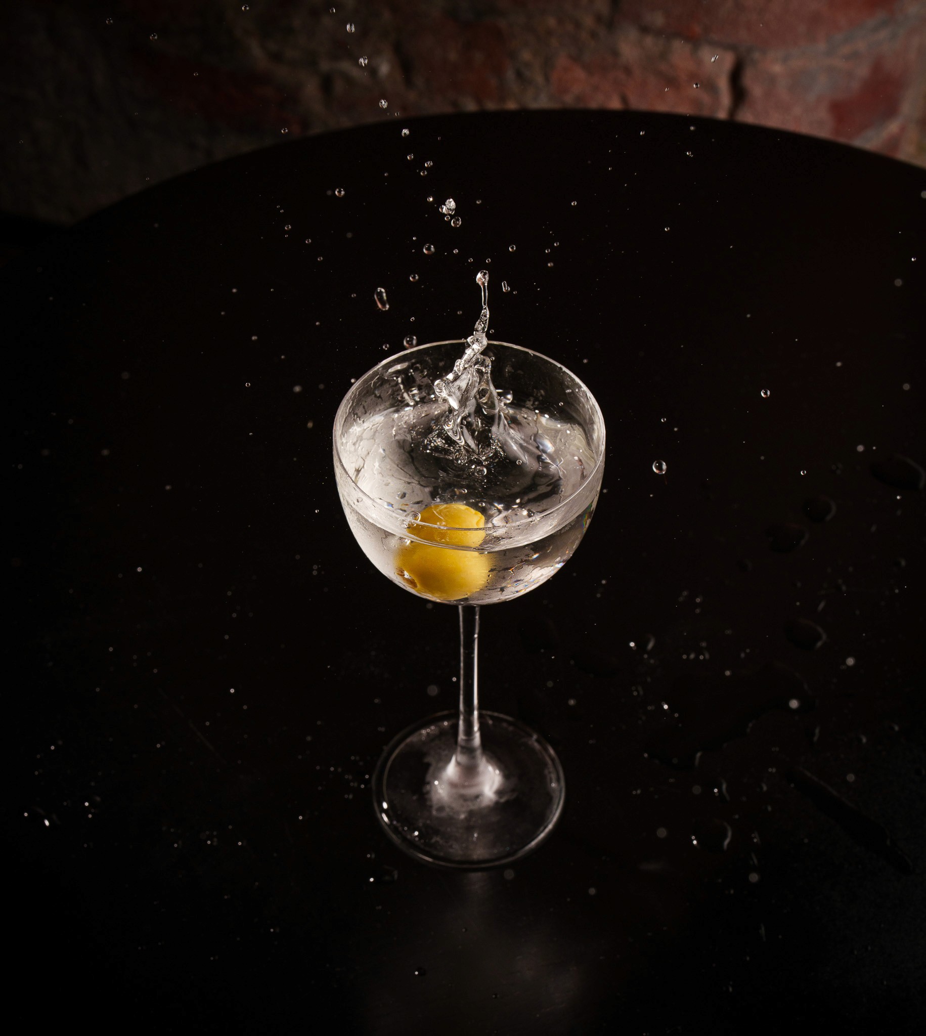 Wooden outdoor table set with multiple plates of food, including dips, salads, potatoes with cheese, and glasses of water, with hands reaching in to eat.