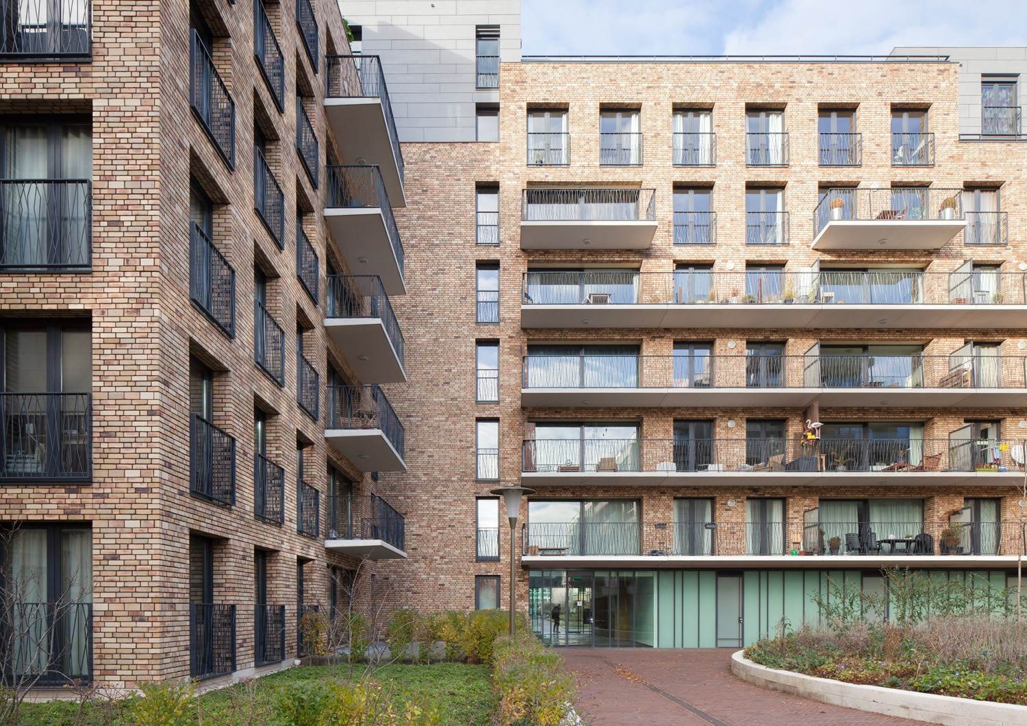 Modern bakstenen appartementsgebouwen met balkons en groenvoorziening rondom.