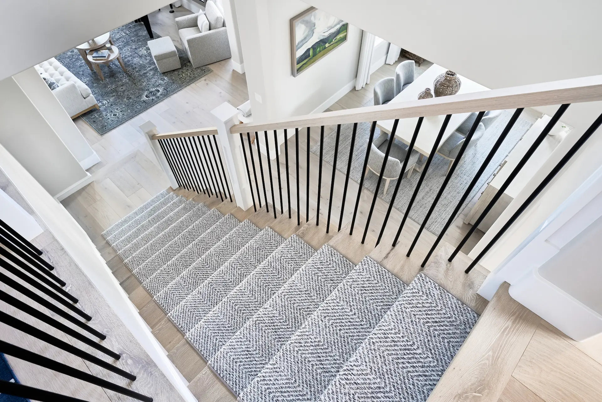 Wide view looking down the staircase, showcasing the stair design and adjacent areas in the Irvine Contemporary Coastal Remodel. Photo by Todd Huge.