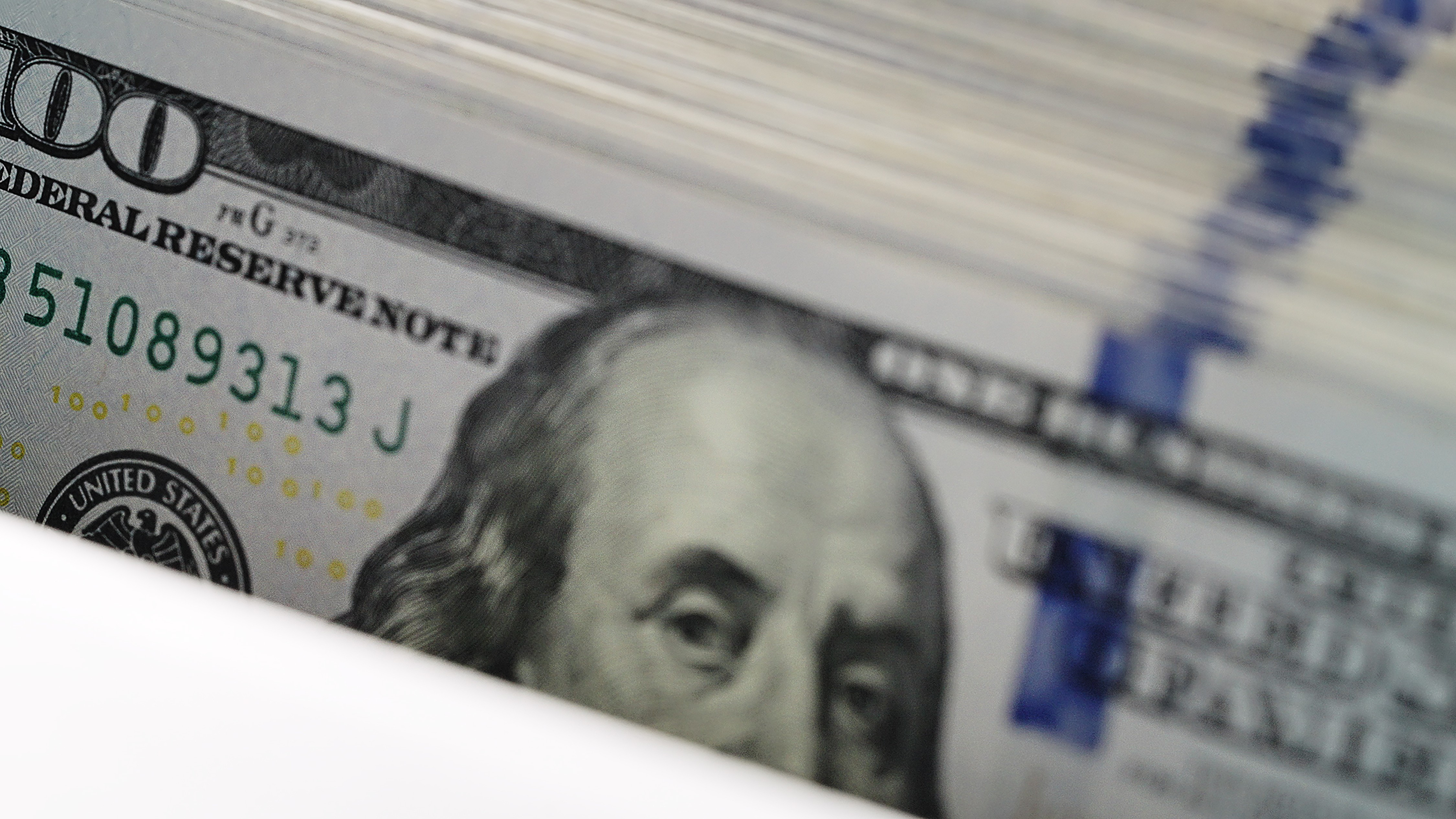  A stack of US 100 dollar bills being counted in an ATM machine
