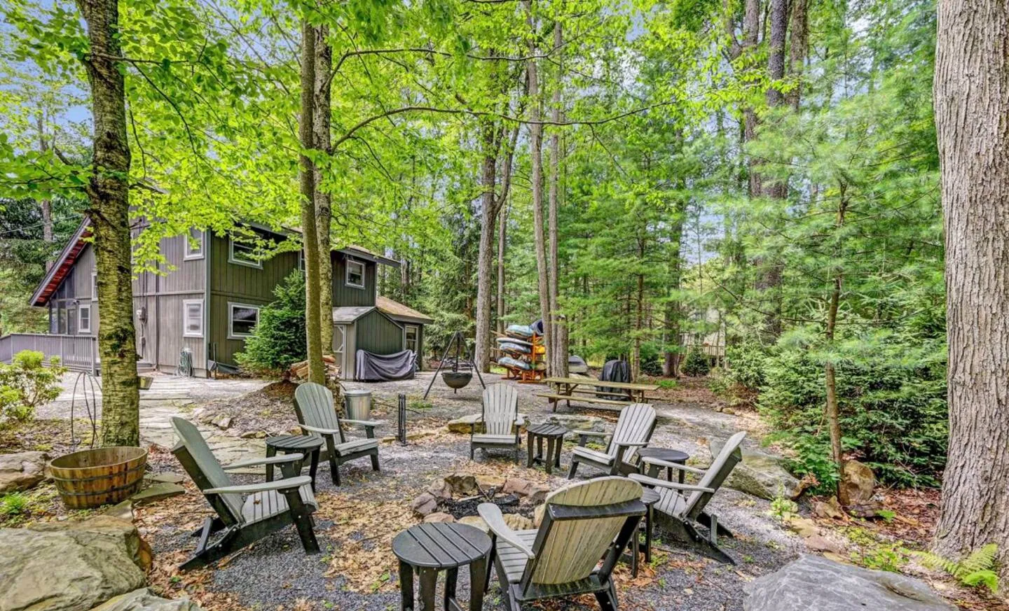 Fire pit patio with Adirondack chairs among rocks and trees at Mountain MAMA, Lake Naomi, Pocono Pines