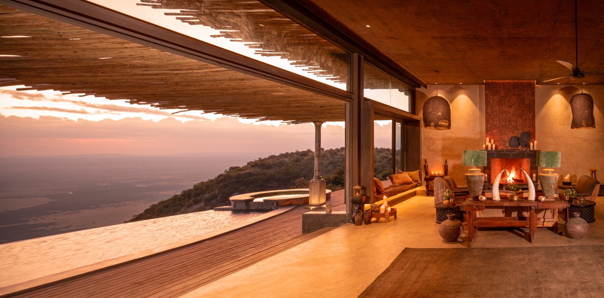 A clifftop suite's lounge and lap pool at sunset
