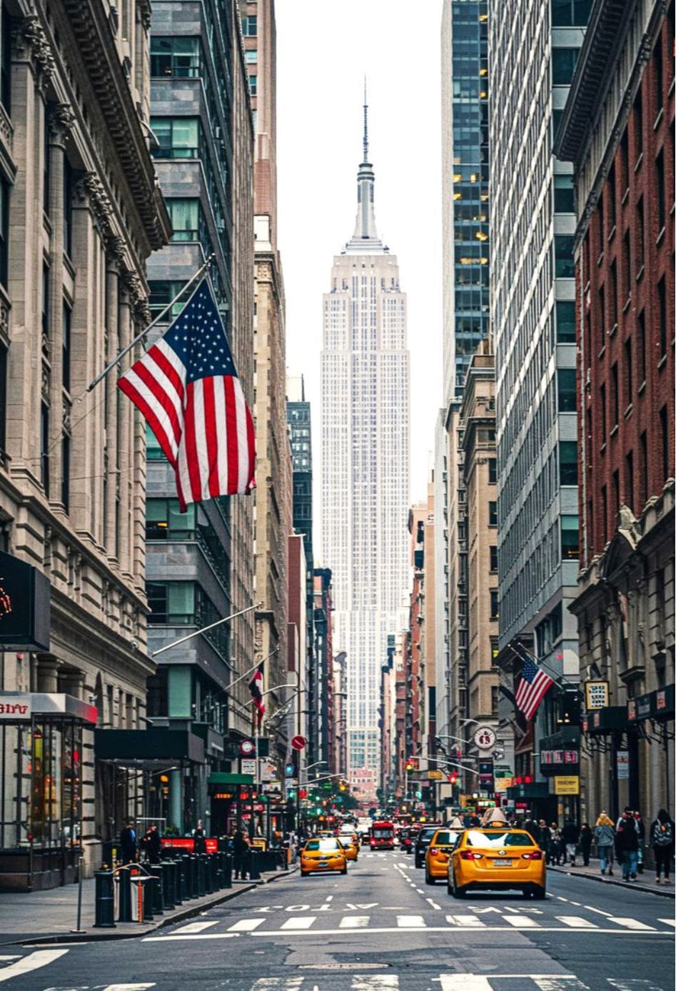 Smiling young man with short hair poses against a dark background, wearing a green button-up shirt.