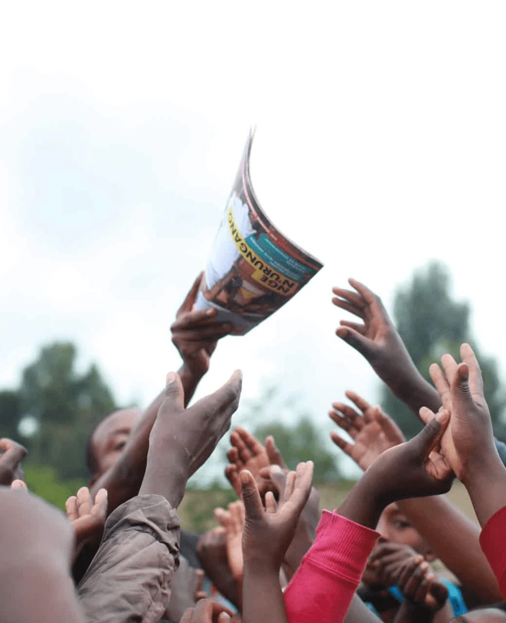 Hands reaching up to catch a Ni Nyampinga magazine being passed over a crowd