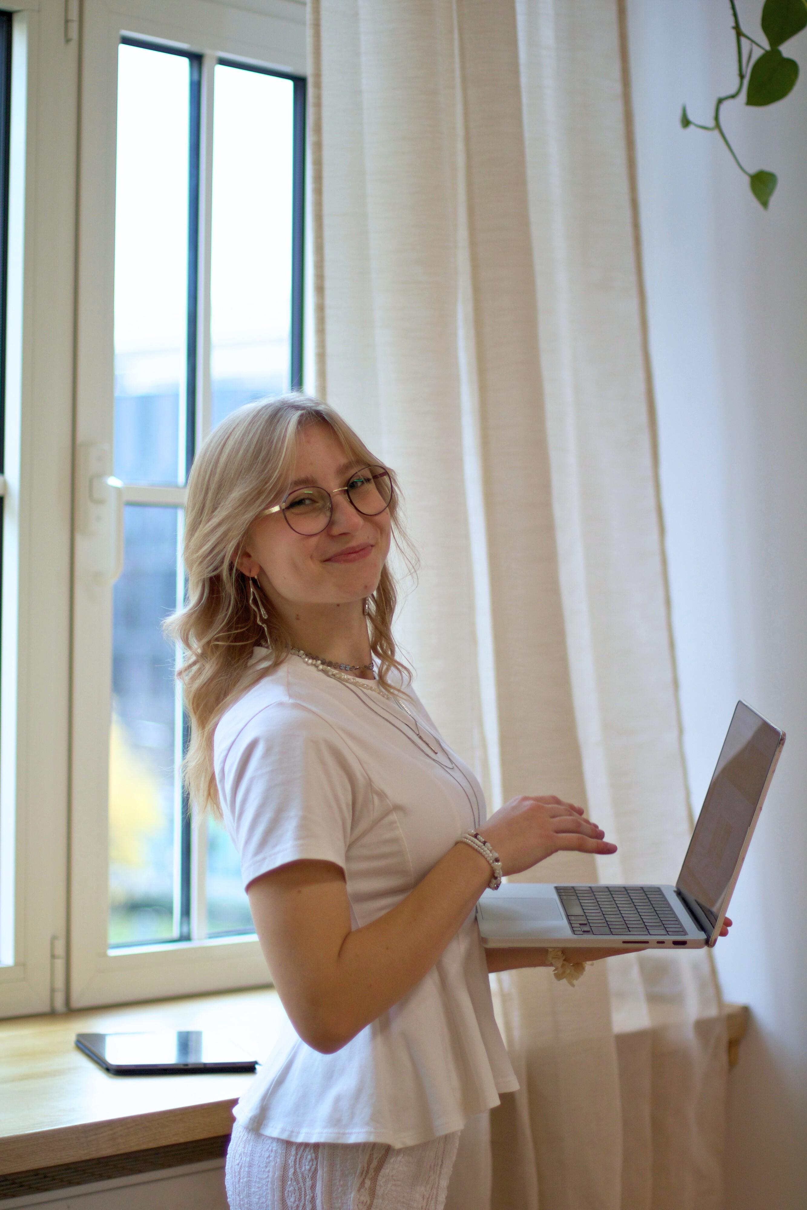 Yasmin steht seitlich zur Kamera und hält ihren Laptop in der Hand