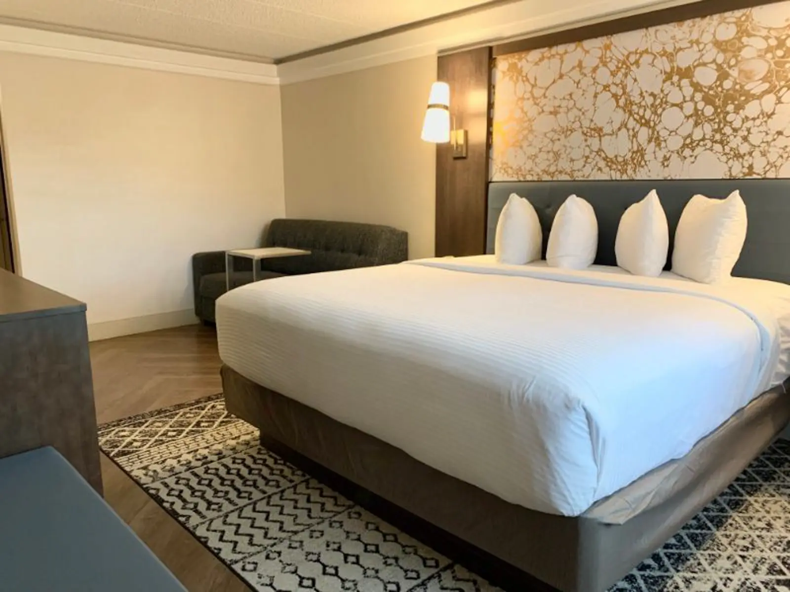 Modern hotel room with a large bed, a decorative headboard, and a sofa.