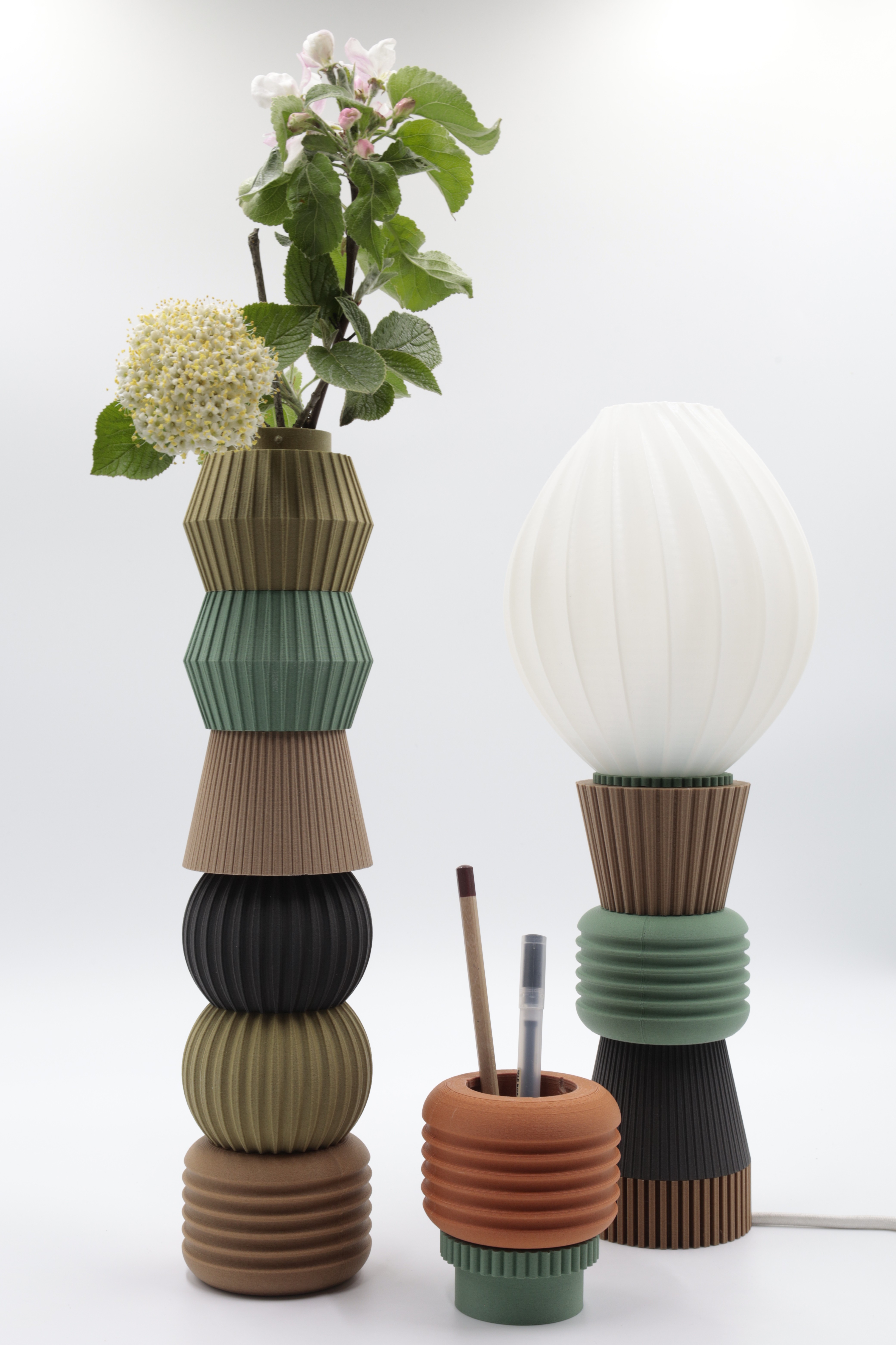 A collection of modern, modular vases and a lamp showcasing an elegant and playful design that combines functionality with a unique aesthetic, integrating flora and light into everyday objects.