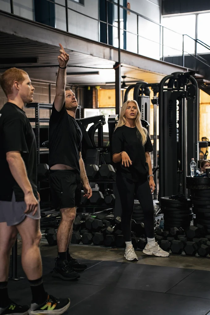 Modern glass and wood cabin with a cozy outdoor deck featuring wicker furniture, surrounded by lush green trees and a serene forest setting.