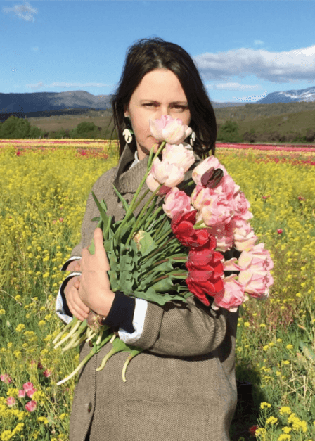 Irina Khatsernova en campo de flores sosteniendo tulipanes — artista floral argentina inspirada por la naturaleza patagónica.