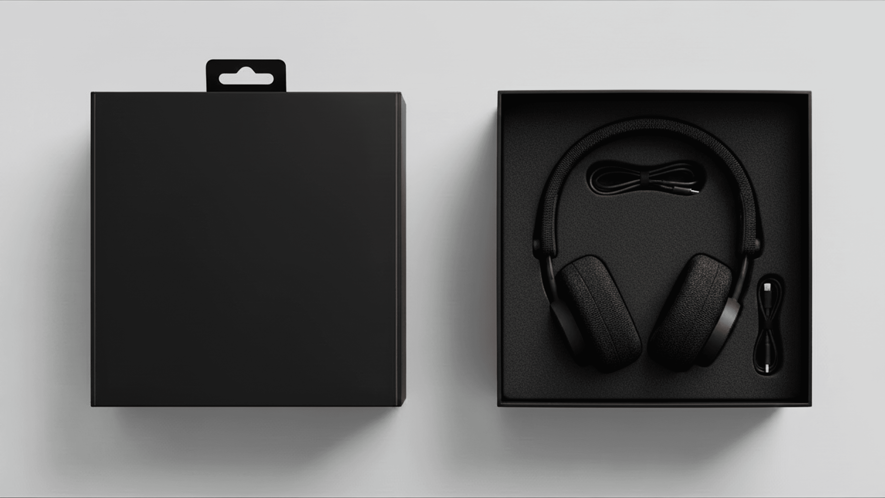 Overhead view of the premium black packaging, showing the headphones securely nested alongside a charging cable in a sleek, square box.