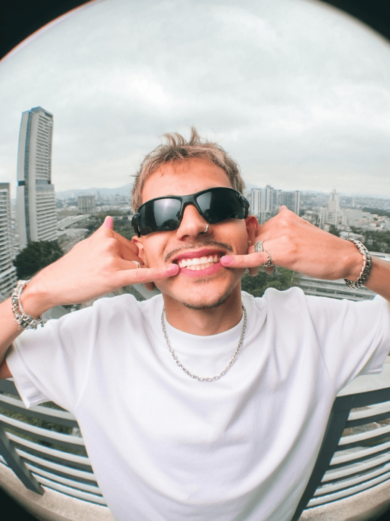 Man making a playful hand gesture on a city balcony