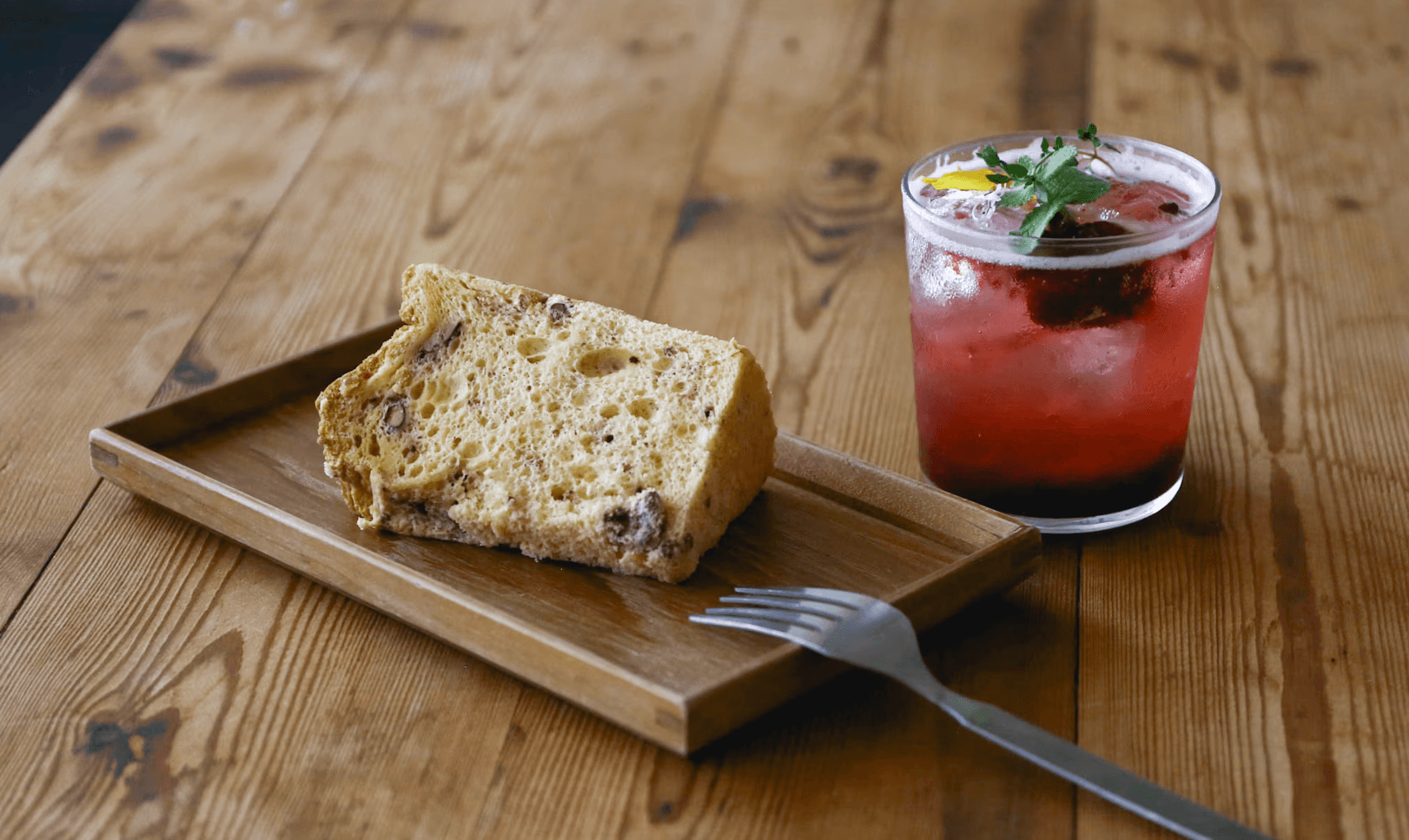 Sponge cake on a wooden plate with a fresh berry soda drink