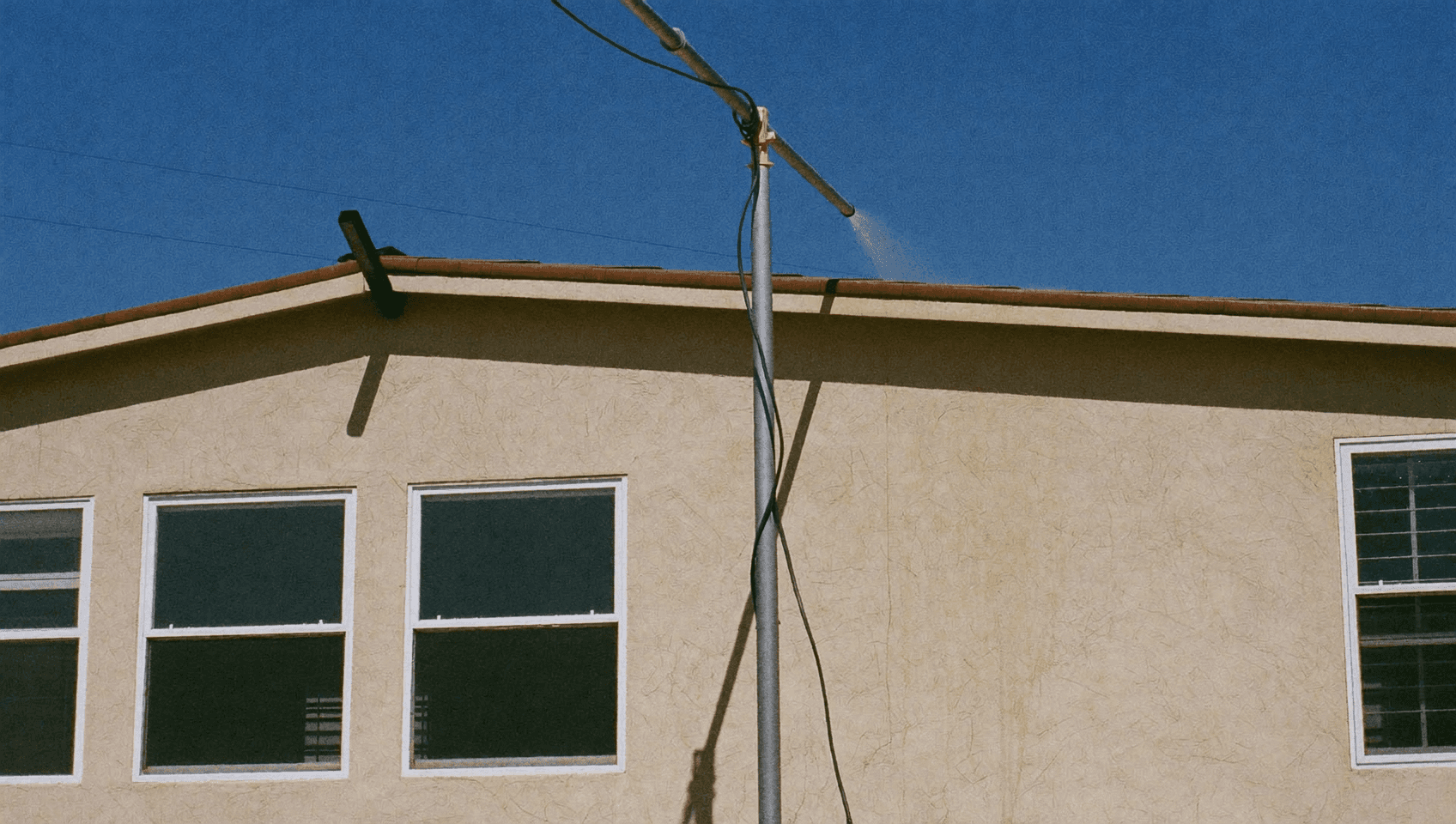 Water-fed pole spraying to clean the high exterior of a stucco home