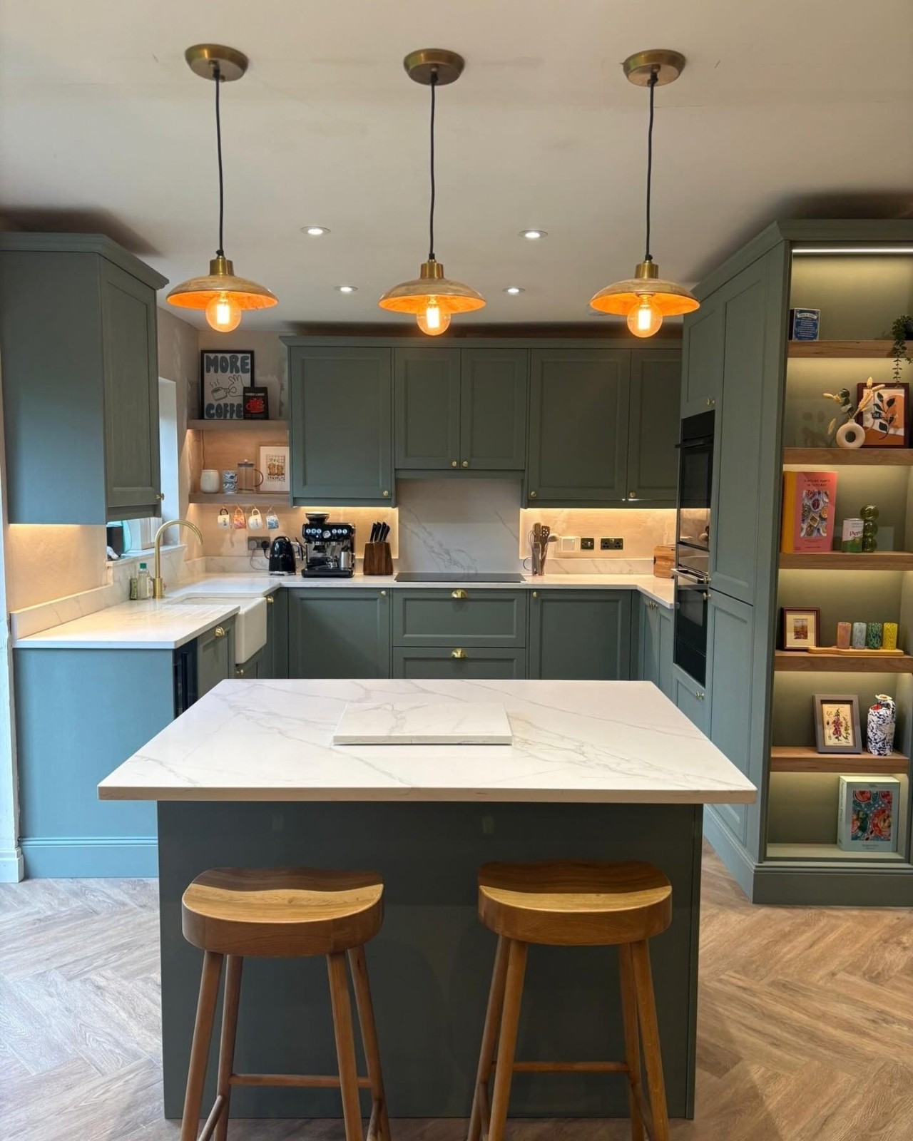 Green shaker kitchen with copper pendant lights and oak bar stools