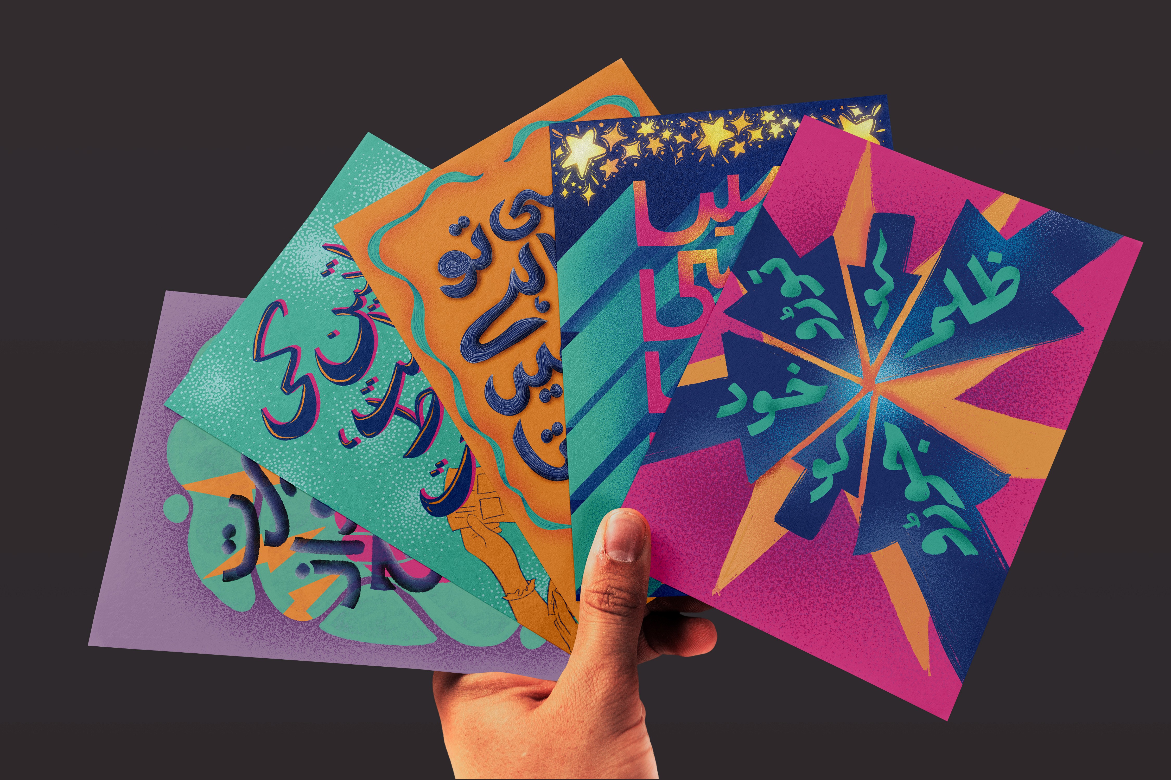 hand holding a collection of 4 graphic design cards, each with unique colors and styles, starting from a off-purple poster, to a turqoise poster, to an orange one and then blue and pink. Each poster has a unique arabic typography inside it