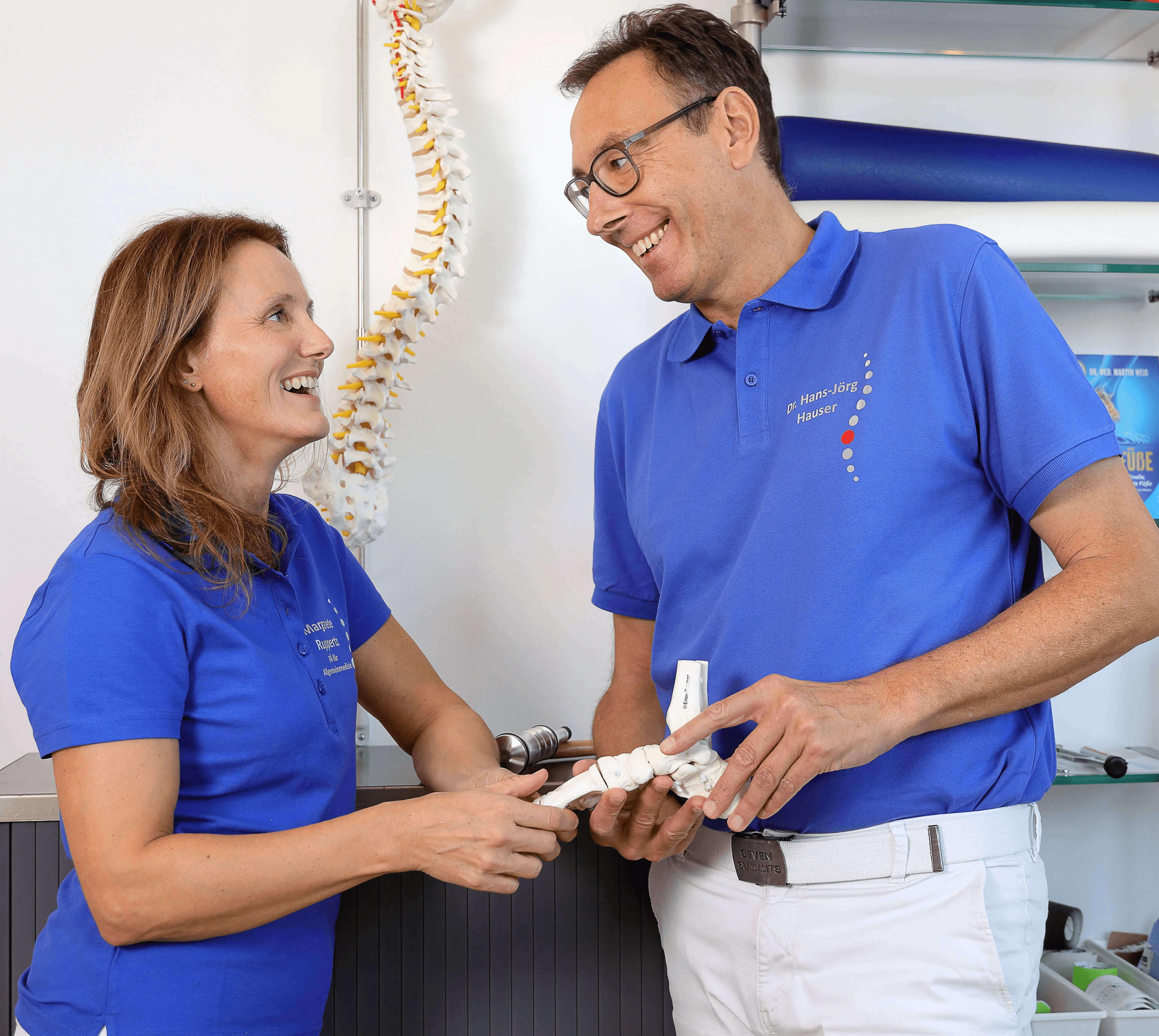 Two people in blue shirts smile and interact while holding an item in a bright, casual setting.