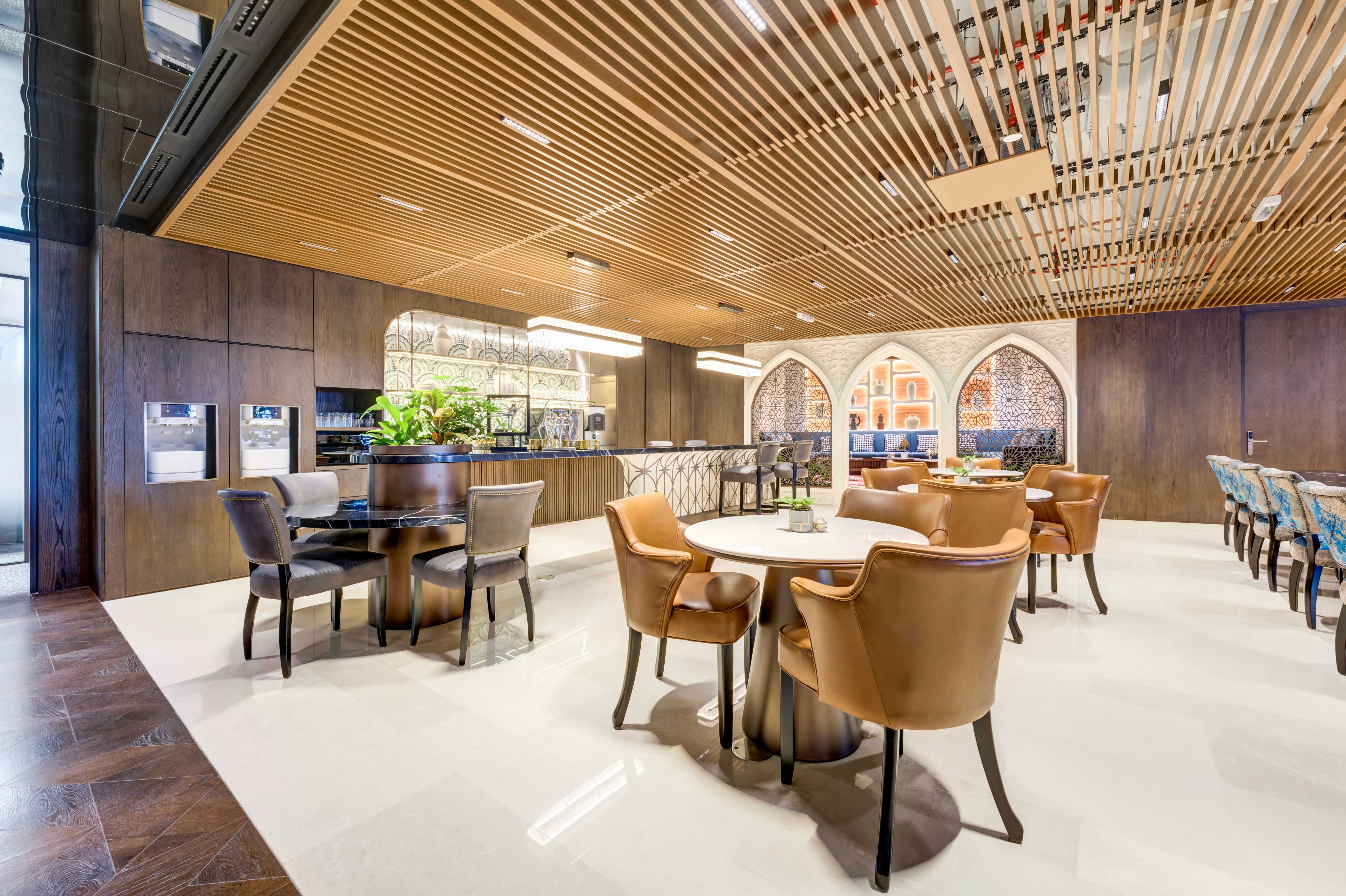 منطقة استراحة عصرية بديكور خشبي وعوارض سقف ظاهرة وإضاءة دائرية في قاعات مناسبات الرياض.