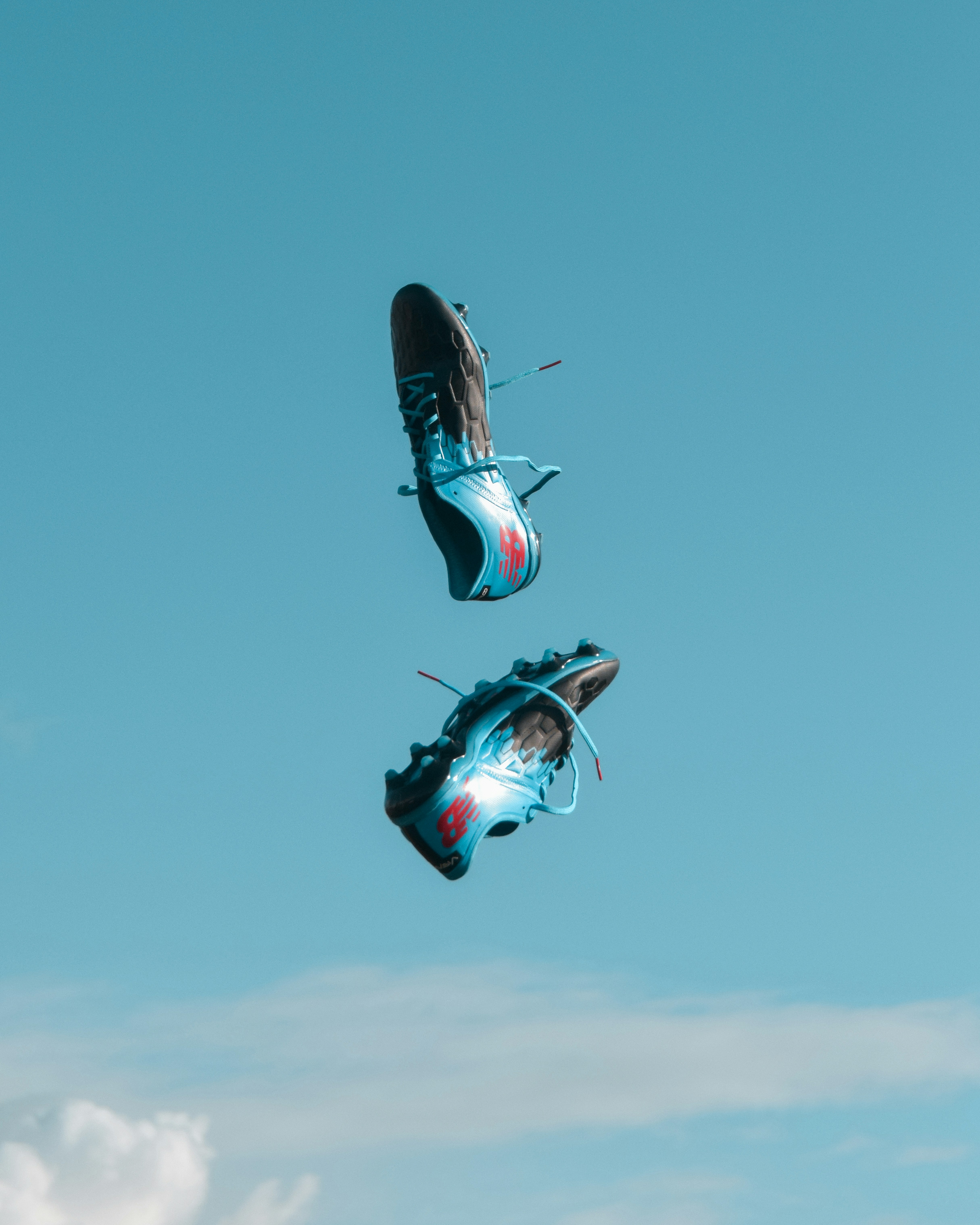 Pair of running shoes floating in the air against a clear blue sky