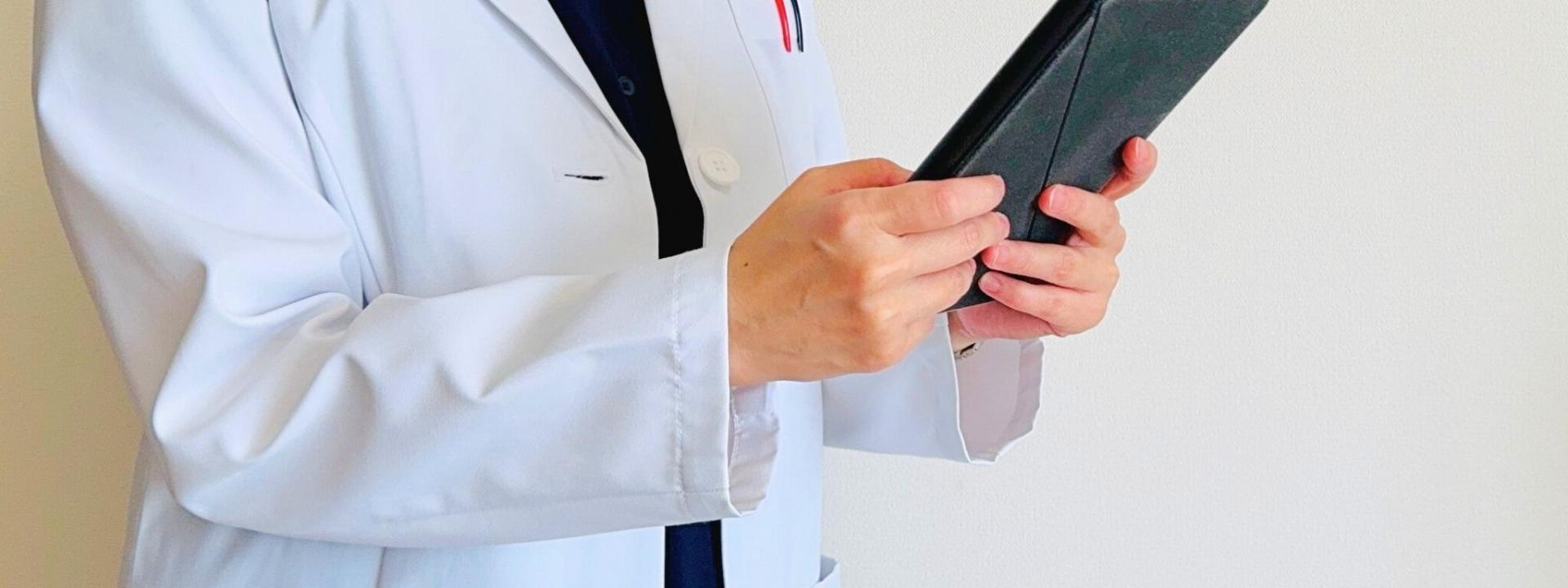 タブレットを操作する白衣の人物（上半身）