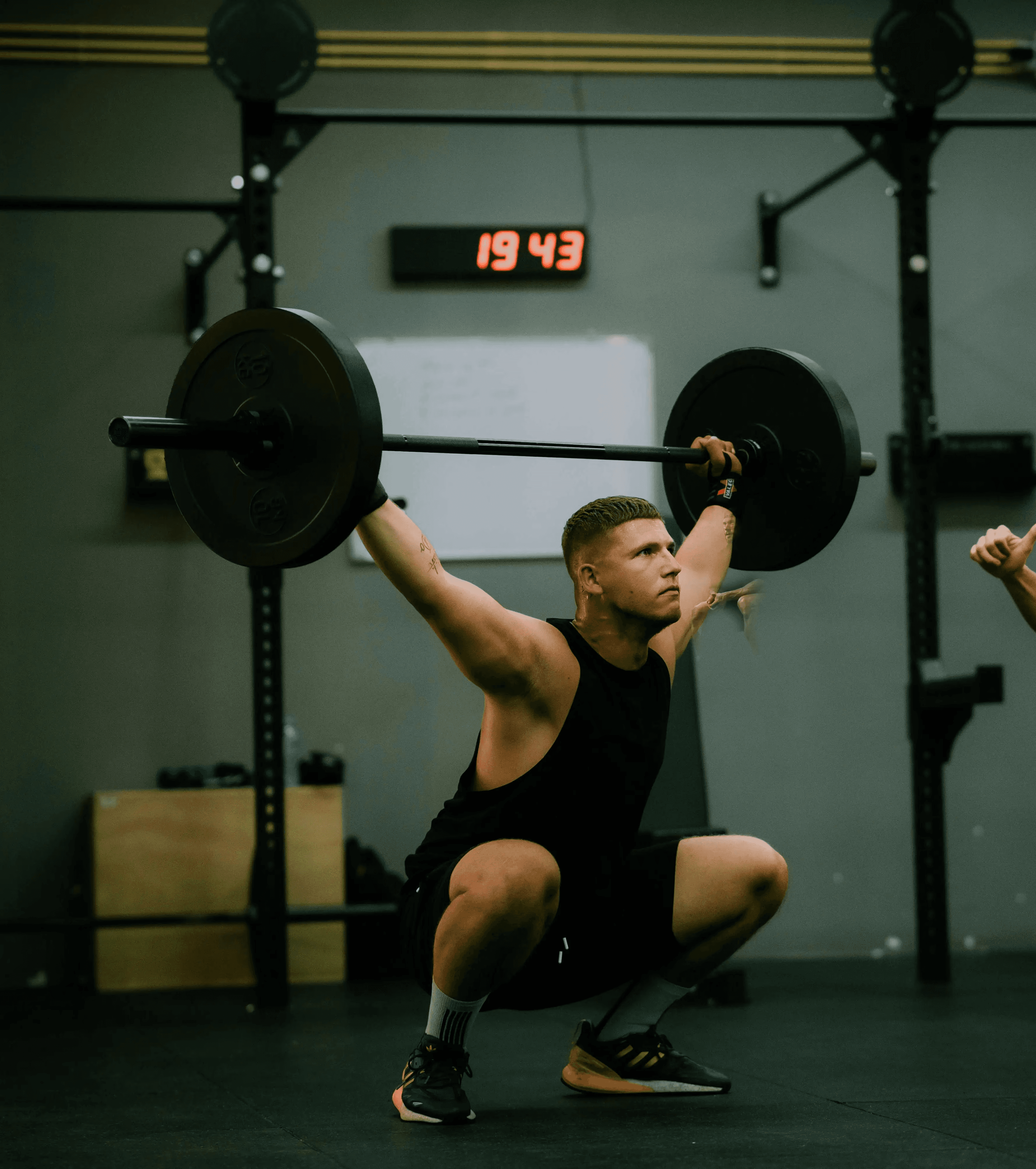 Athlete performs overhead squat in gym.