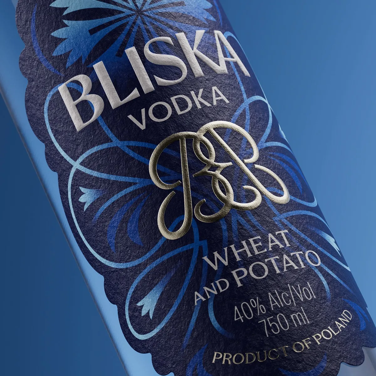 Macro of the Bliska Vodka embossed label with silver foil monogram and scalloped edge, premium label design