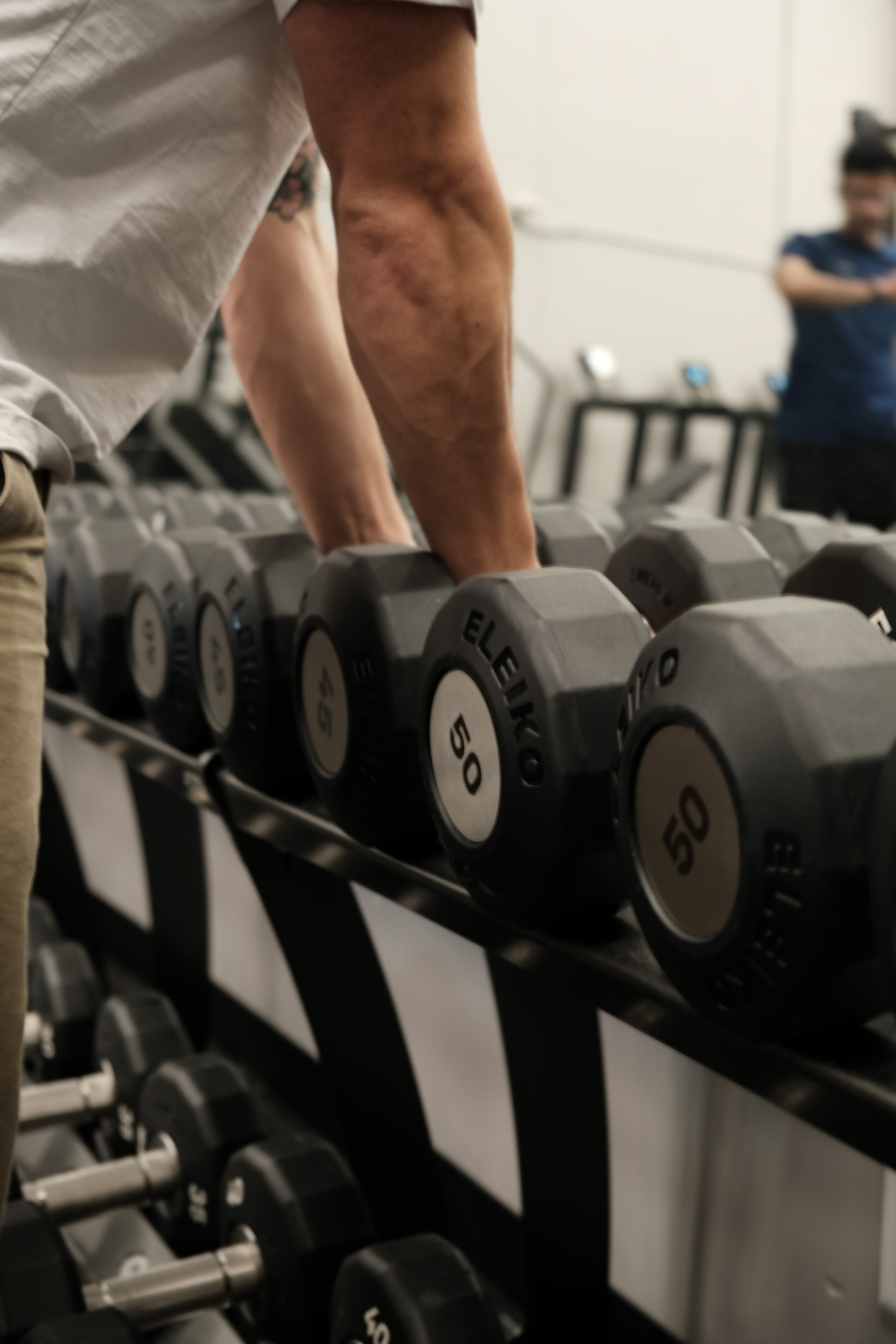 storng hands picking up dumbells from a rack