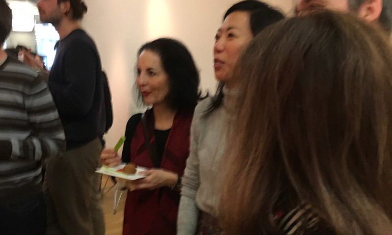 two women having a snack in a room full of people